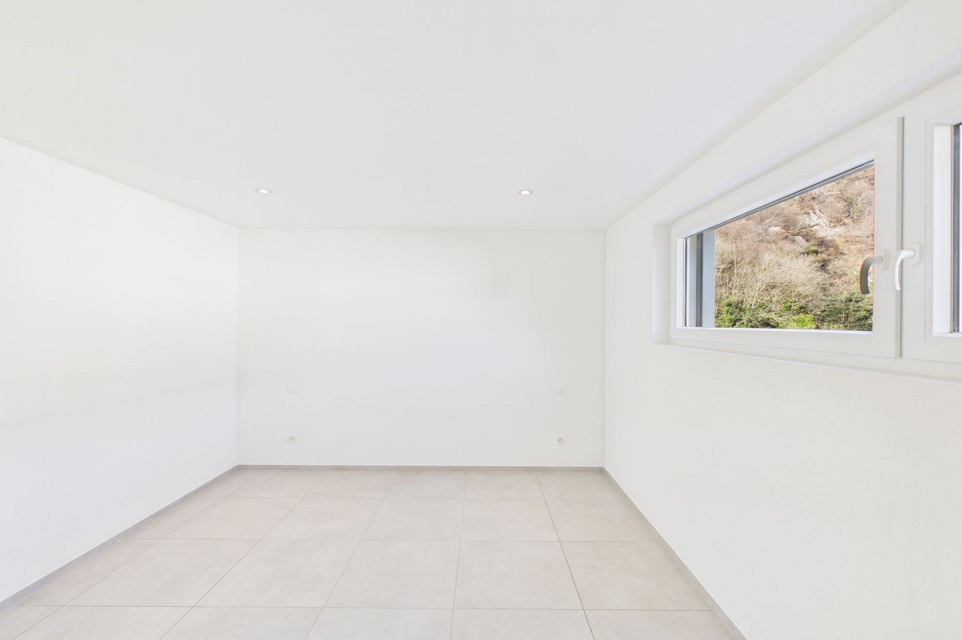 Heller leerer Raum mit Fliesenboden und kleinem Fenster