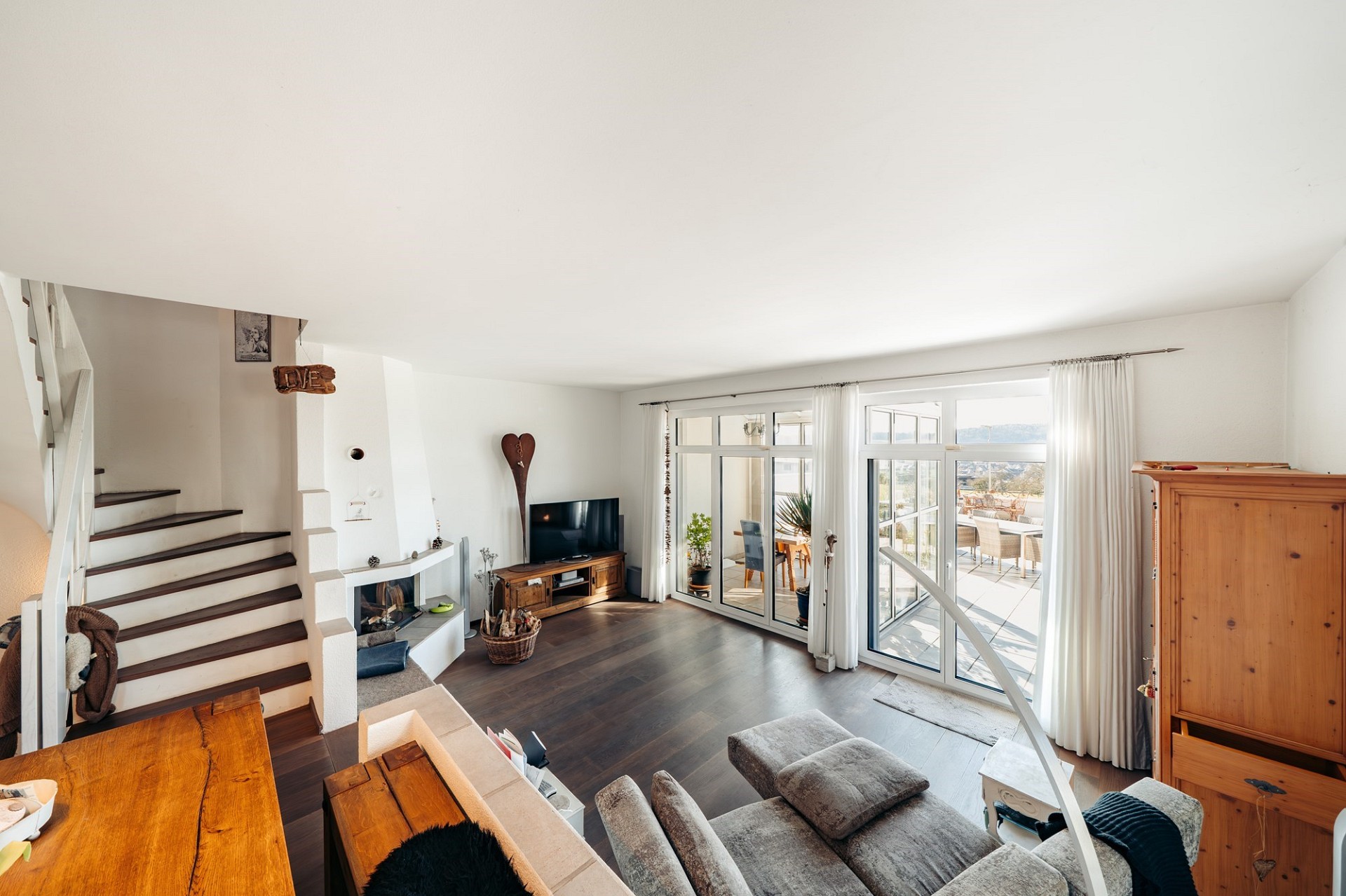 Helles Wohnzimmer mit Treppe, Kamin und Terrassenzugang