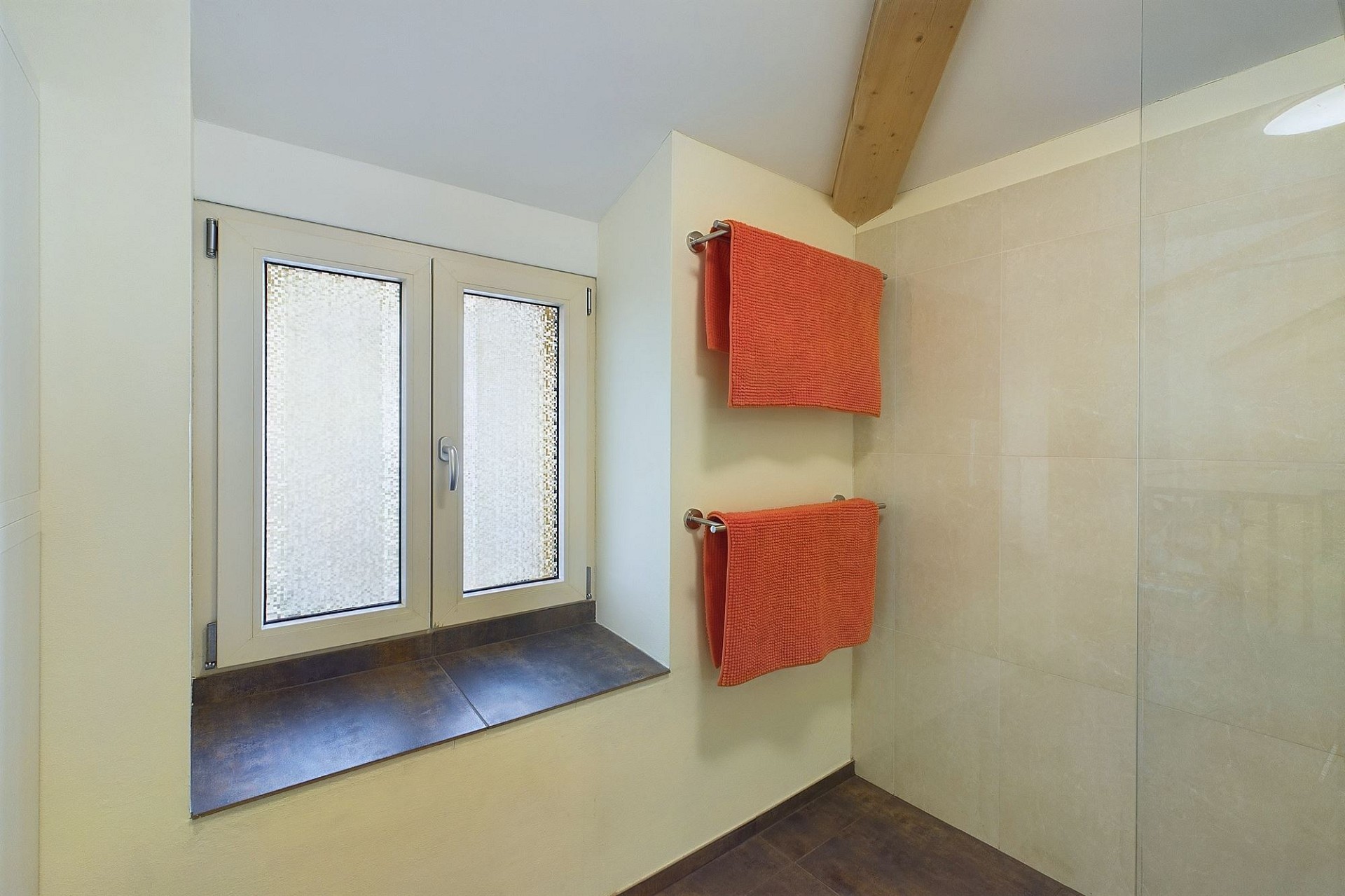 Modernes Badezimmer mit Dachfenster und Handtüchern