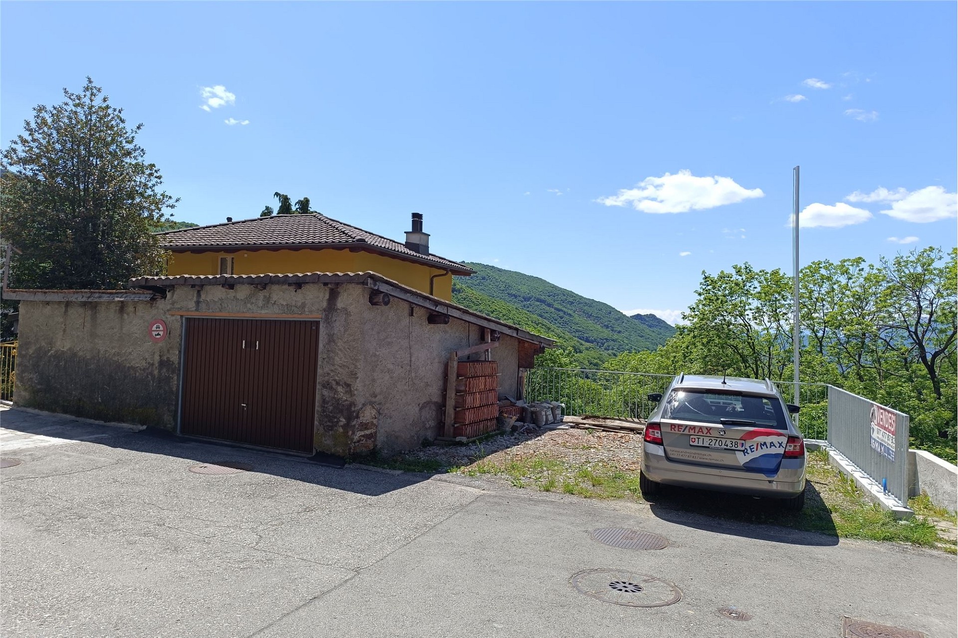 Außenansicht eines ländlichen Grundstücks mit Garage und Bergblick