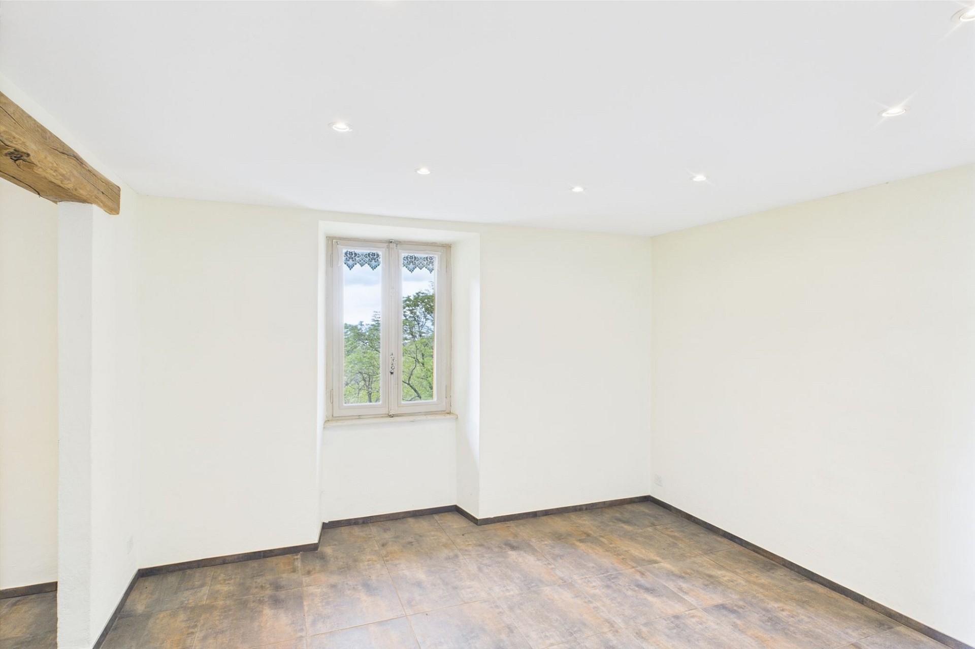 Heller, leerer Raum mit Fenster und Natursteinoptik-Boden