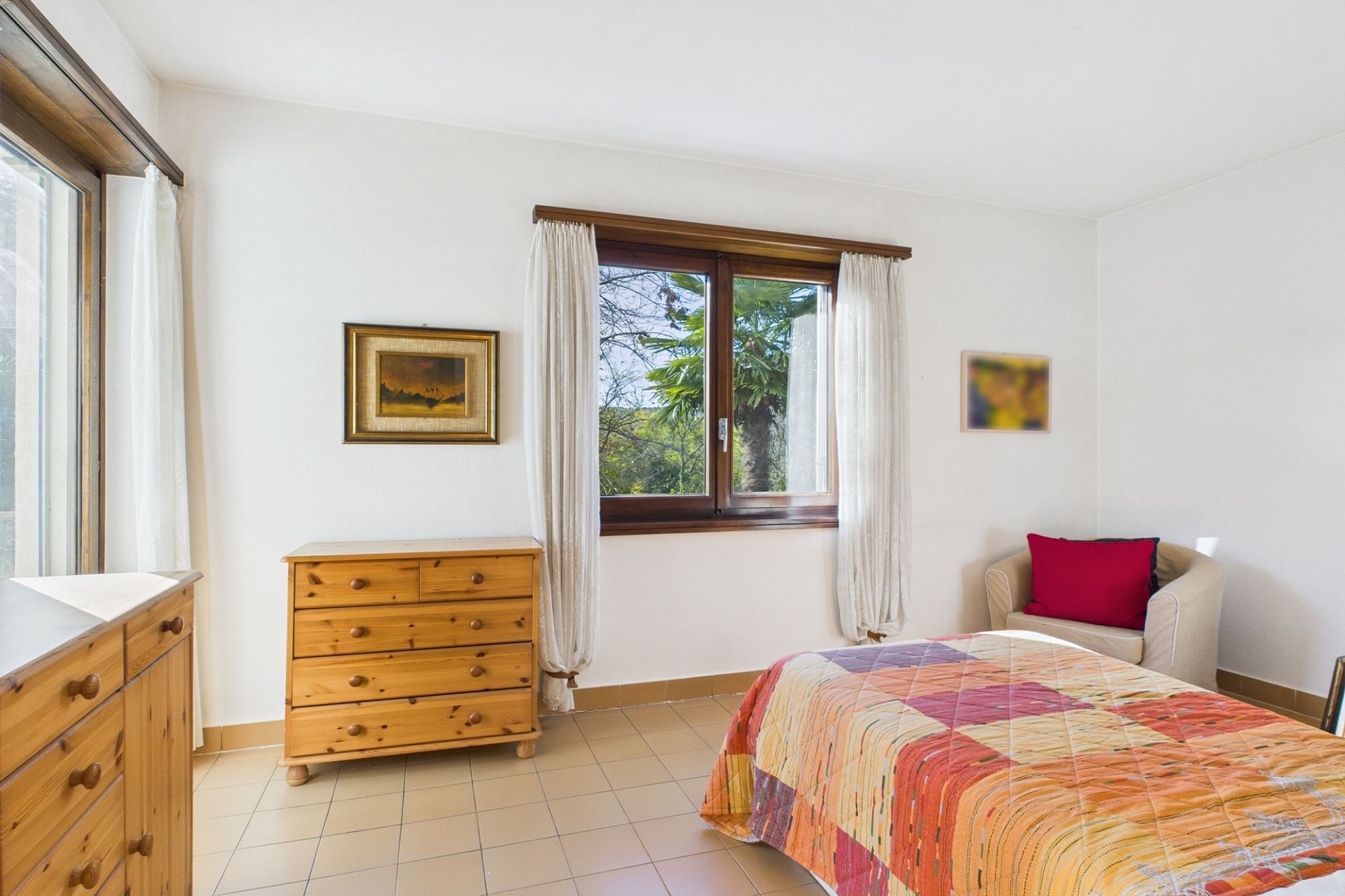 Helles Schlafzimmer mit Holzmöbeln und Blick ins Grüne