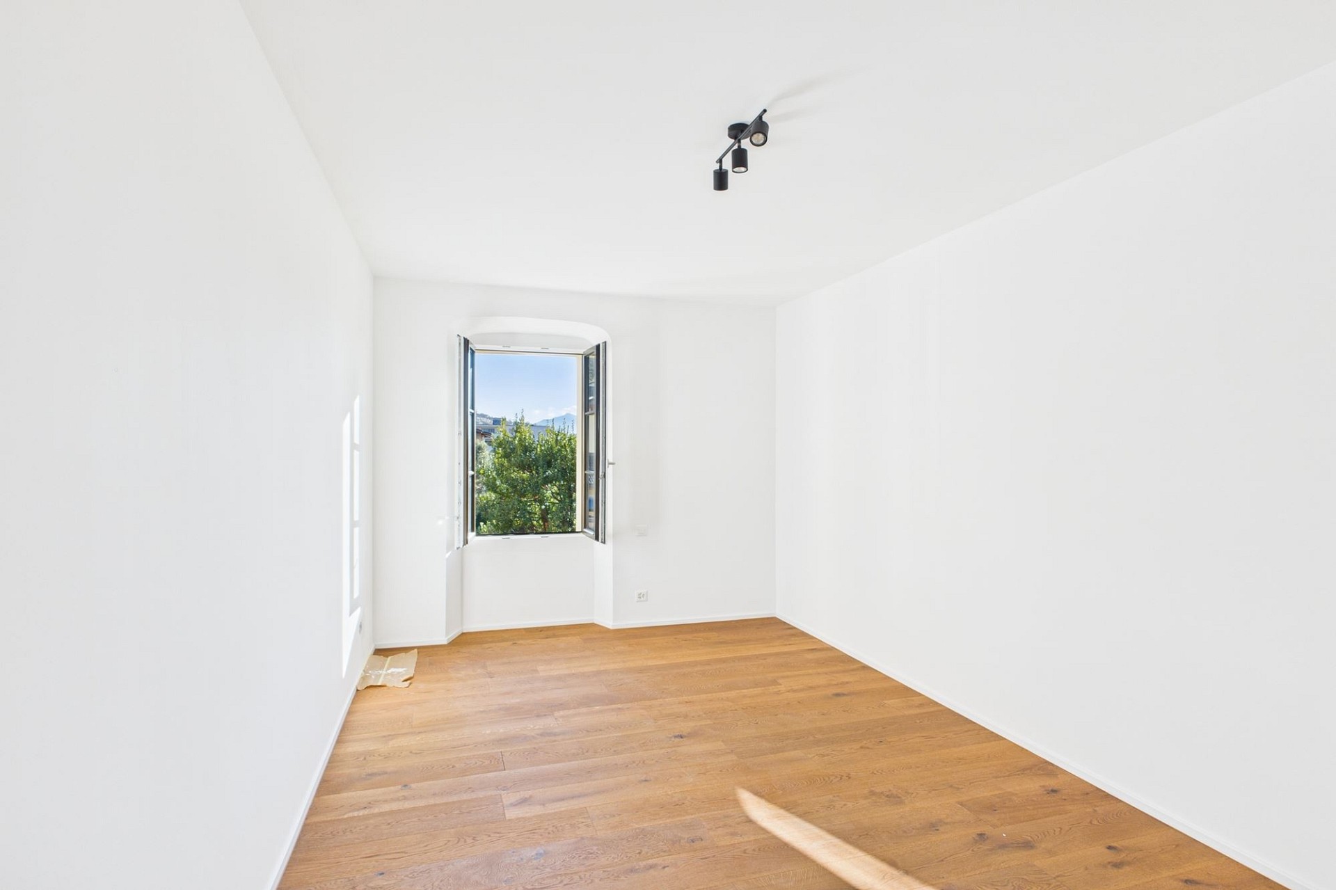 Heller leerer Raum mit Parkettboden und Fensterblick