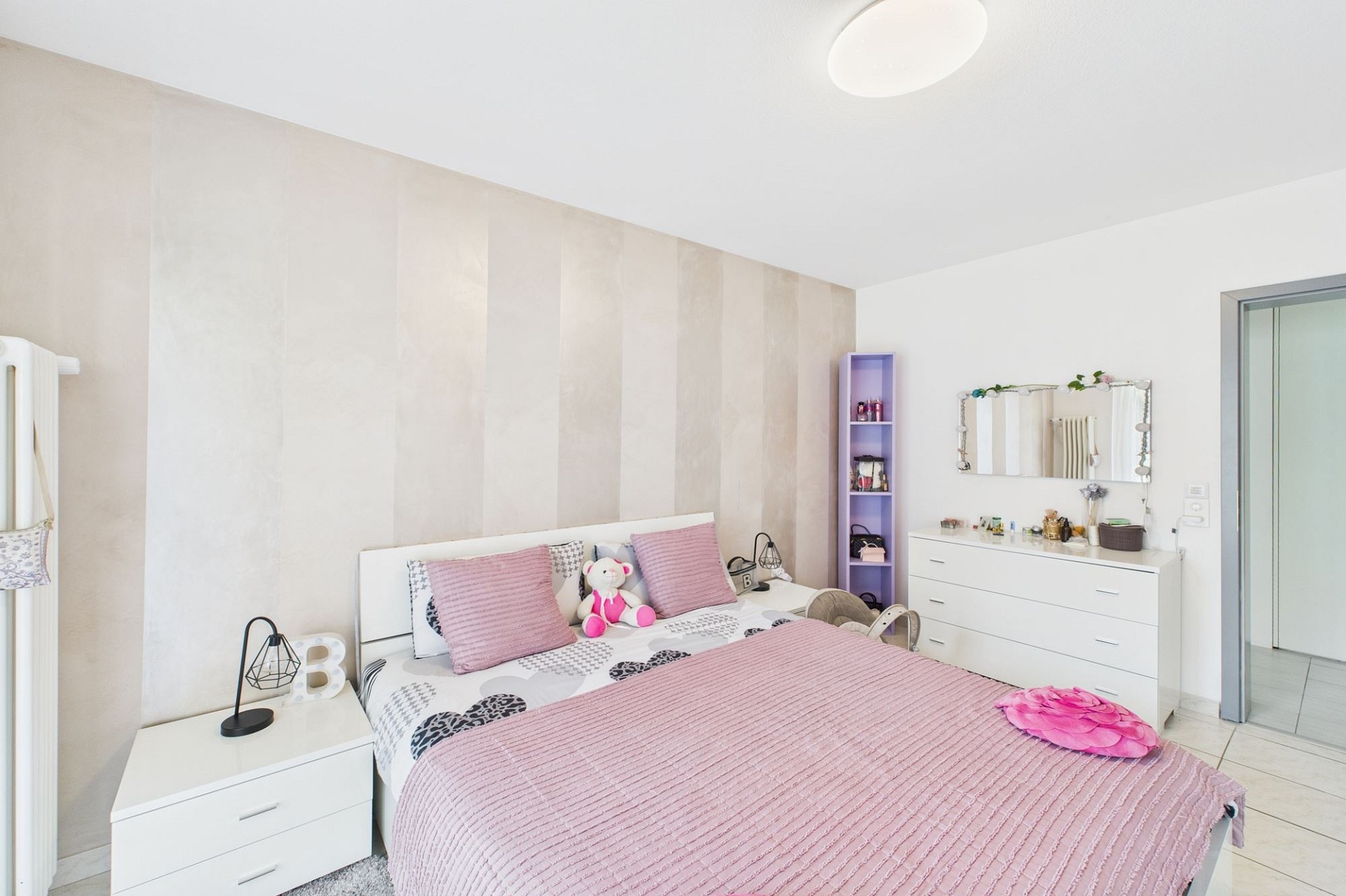 Helles Schlafzimmer mit weißer Einrichtung und rosa Akzenten
