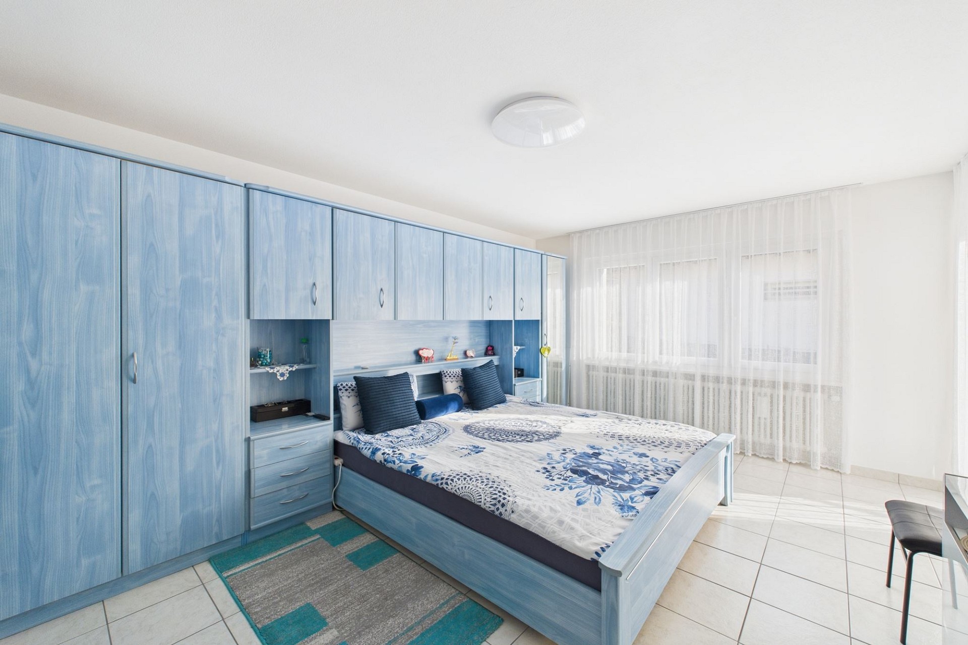 Helles Schlafzimmer mit blauer Einbaumöbelwand
