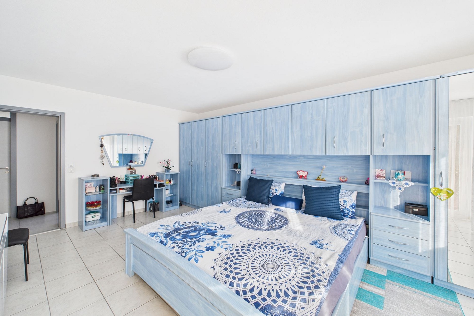 Helles Schlafzimmer mit blauem Kleiderschrank und Schminktisch