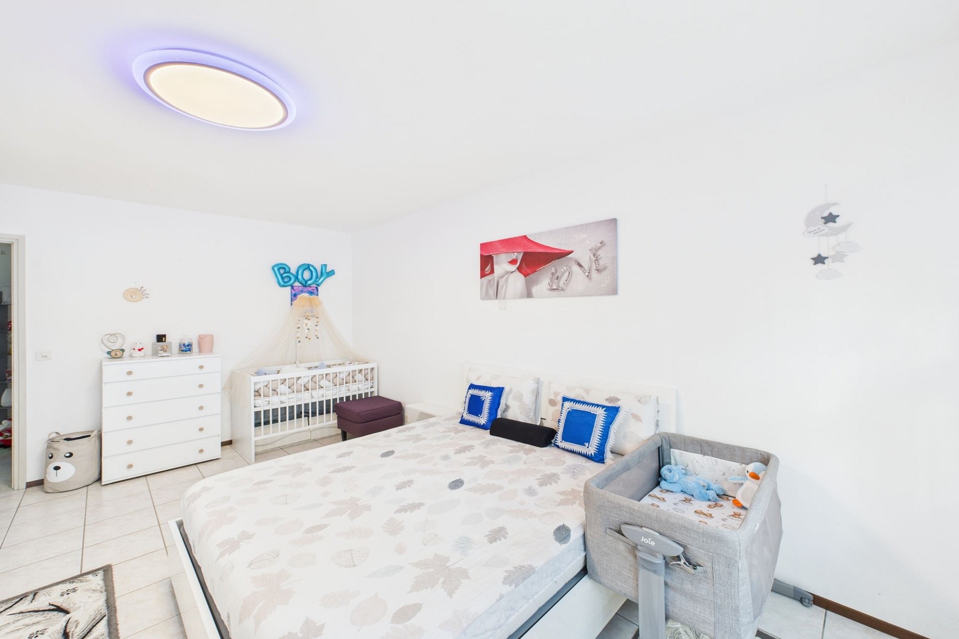 Helles Kinderzimmer mit Babybett und Doppelbett