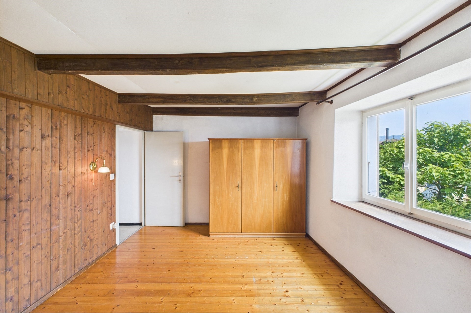 Rustikales Zimmer mit Holzvertäfelung und Fensterblick