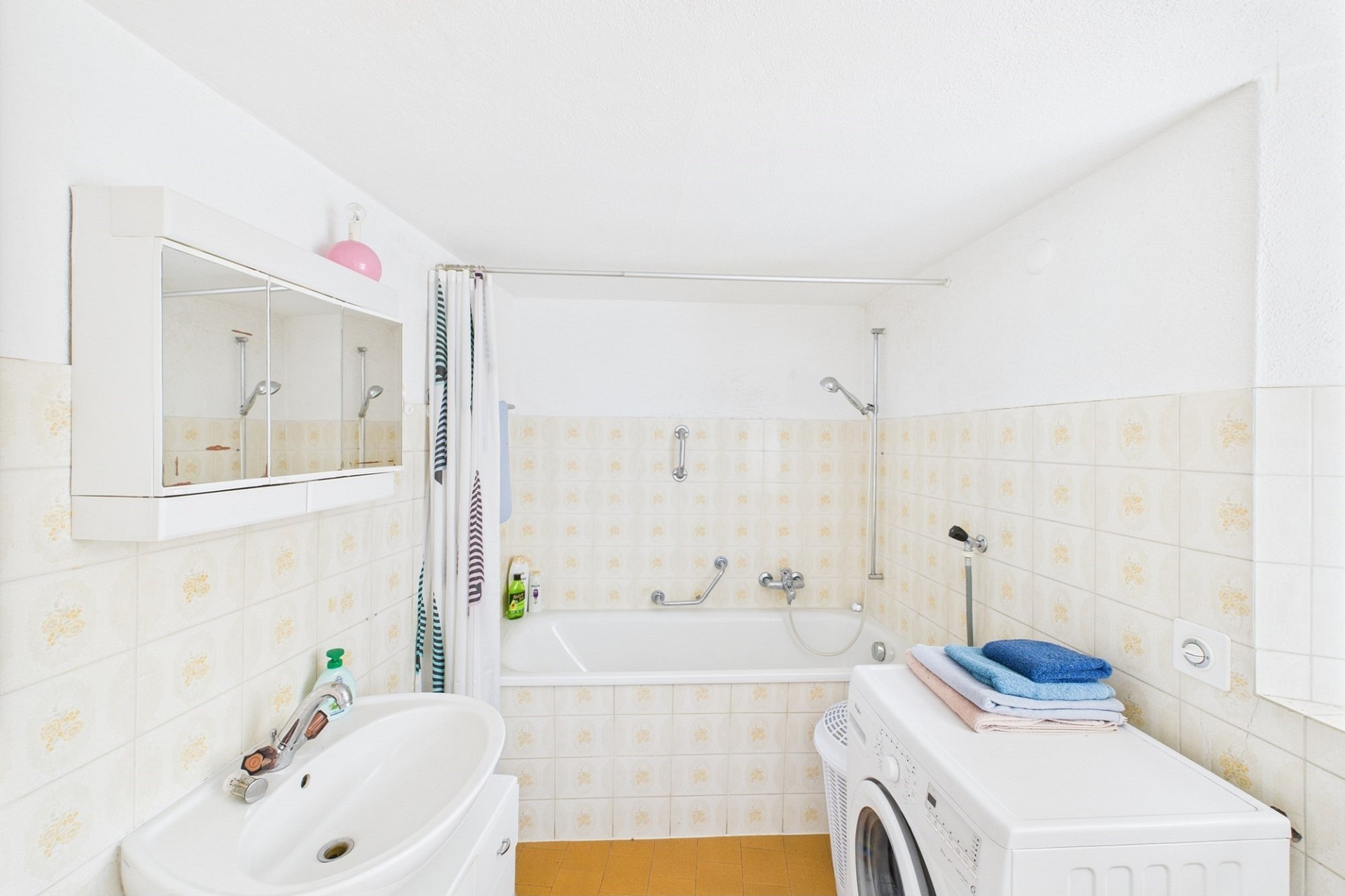 Kleines, schlichtes Badezimmer mit Badewanne und Waschbecken