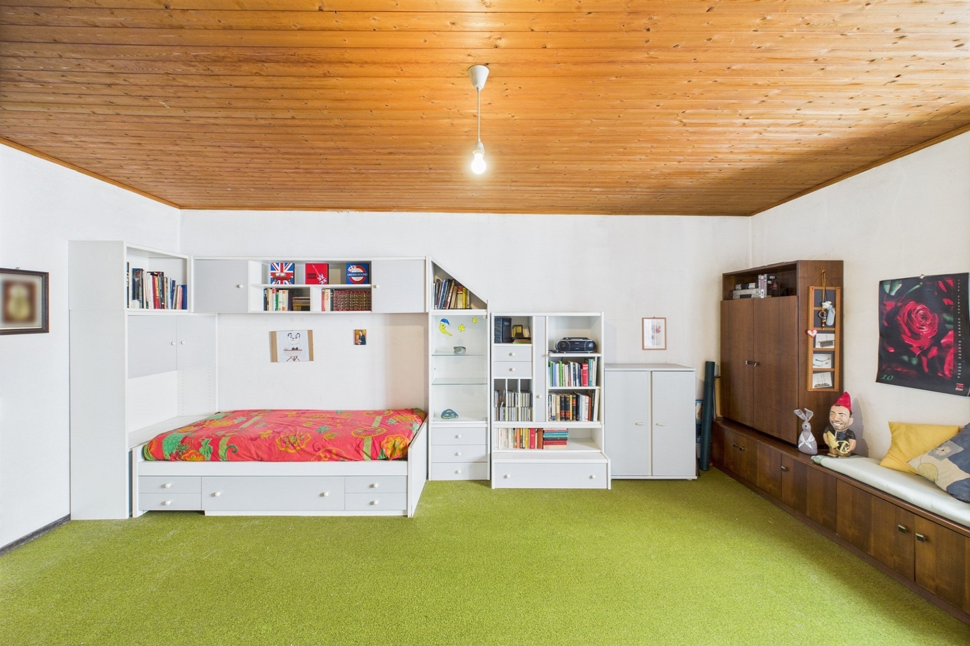 Helles Schlafzimmer mit Holzdecke und grünem Teppich