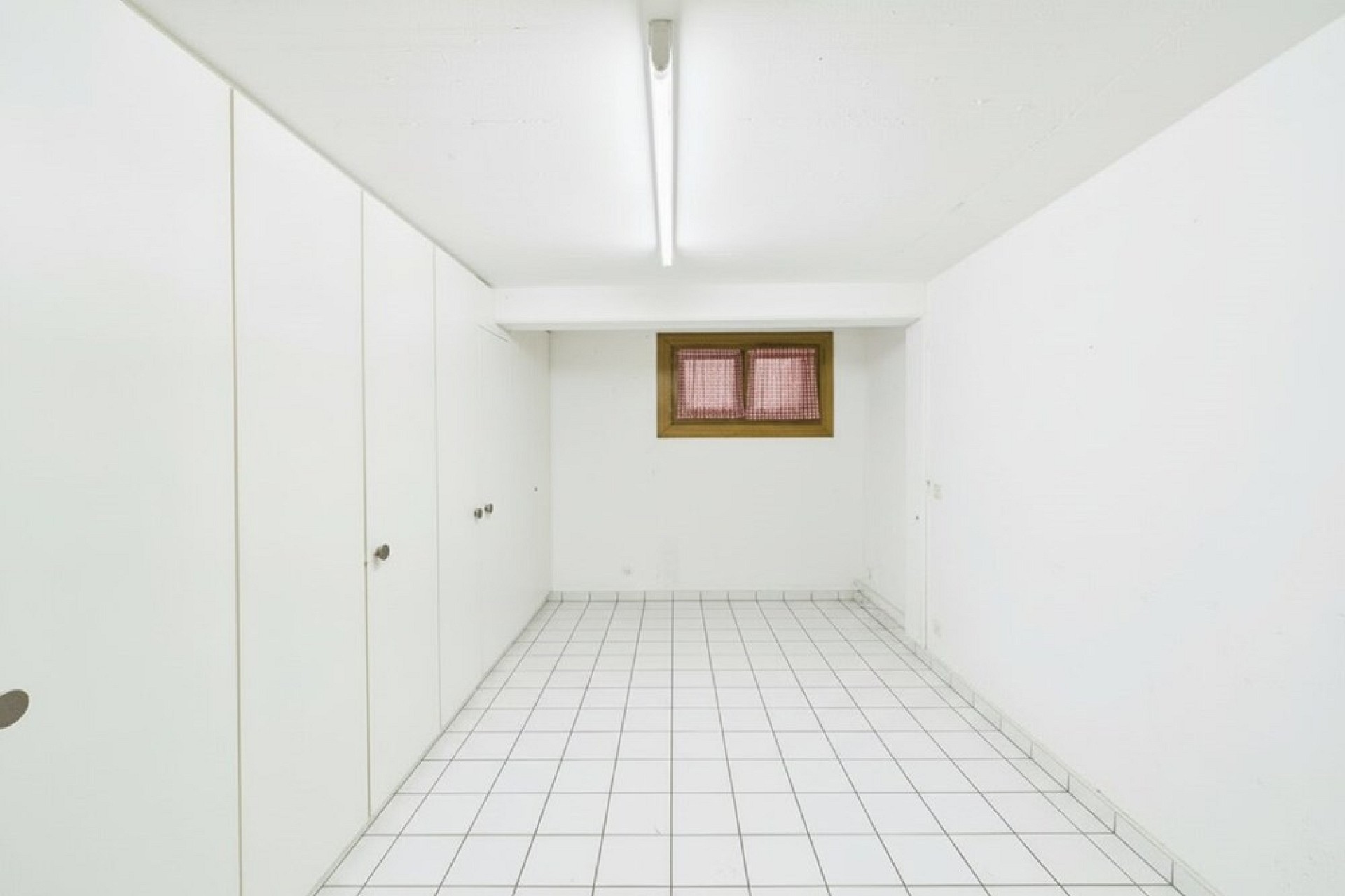 Kleiner weißer Raum mit Fenster und Einbauschränken