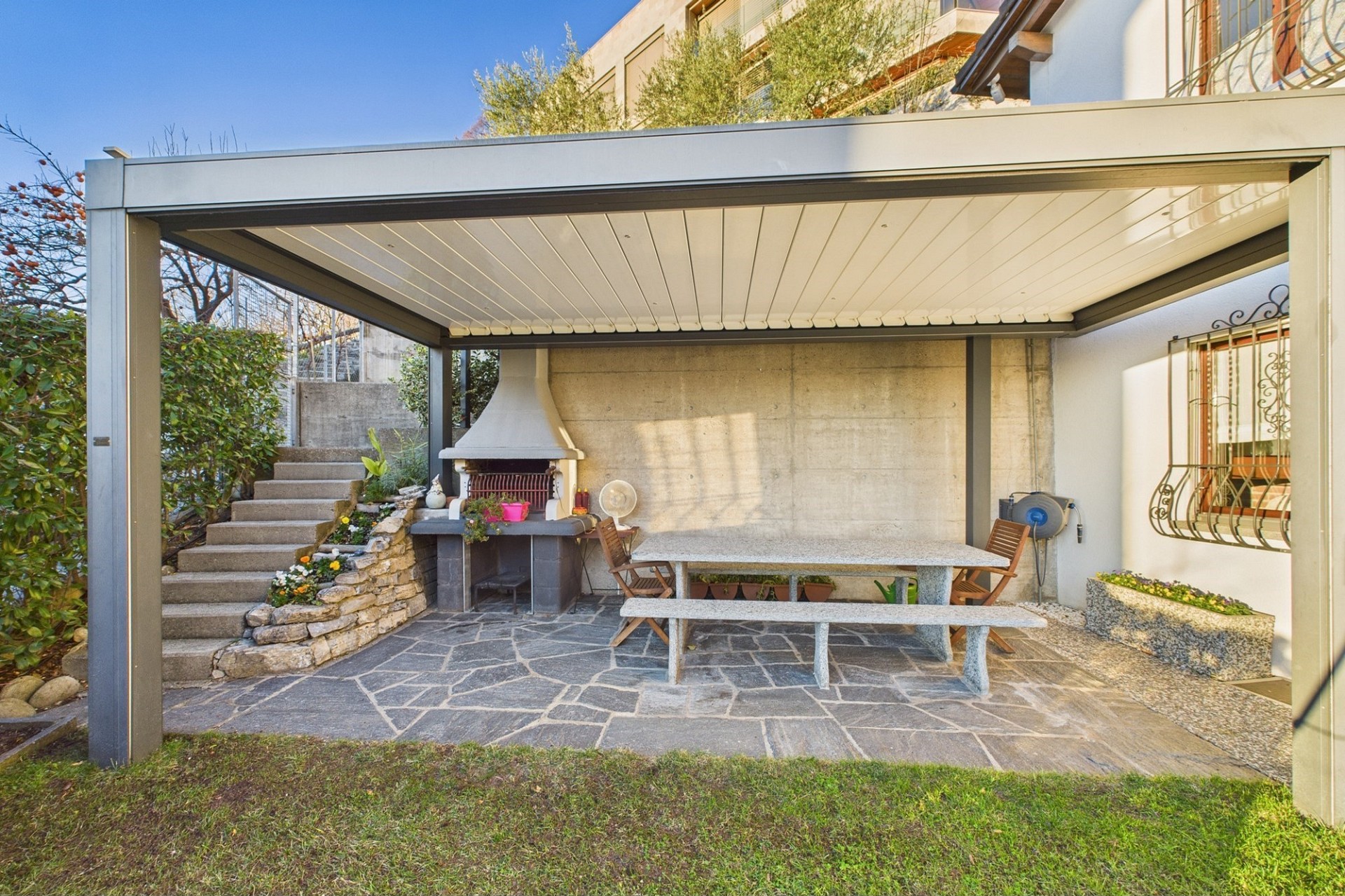 Überdachte Garten-Terrasse mit Grill und Sitzbereich