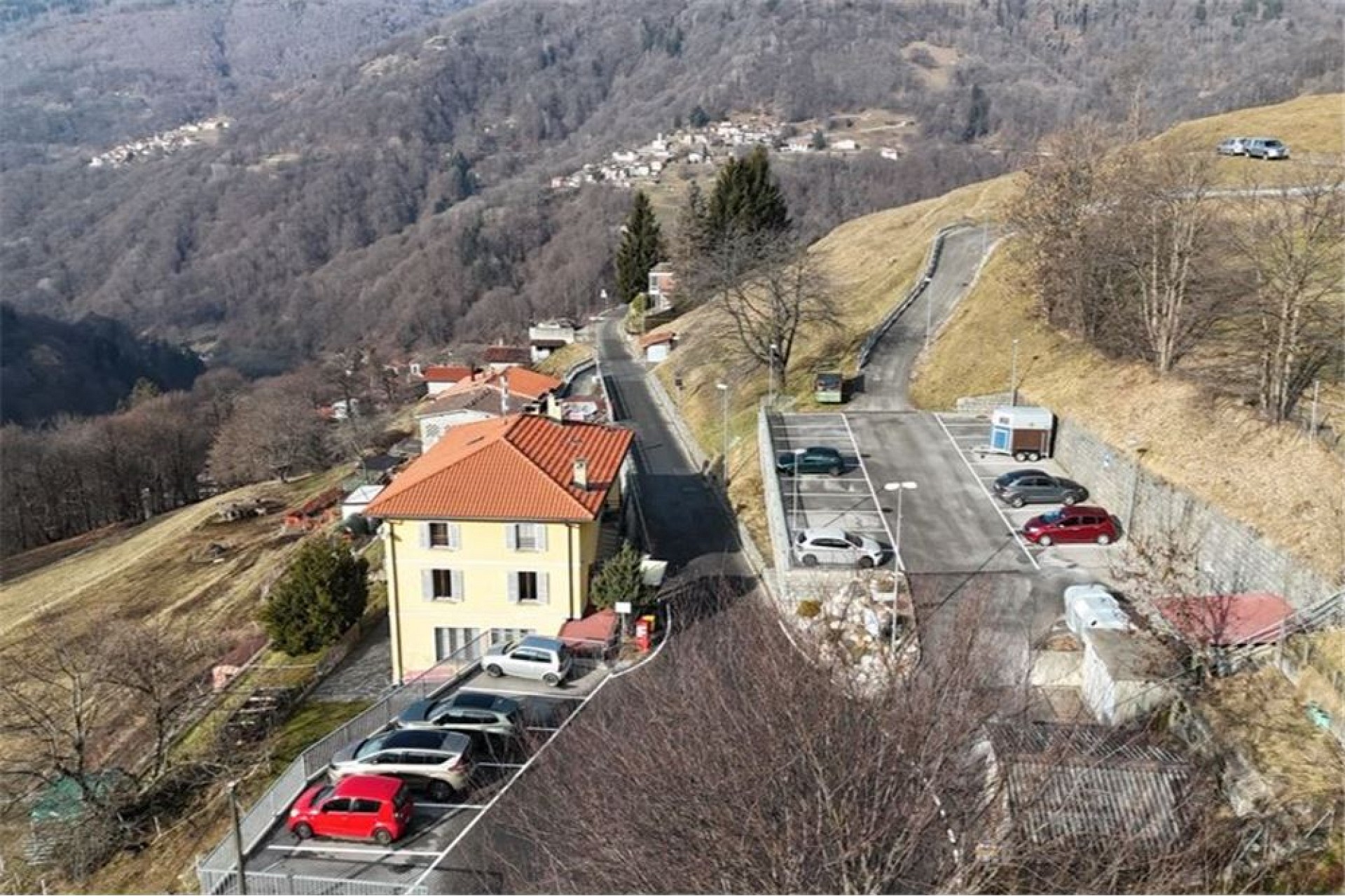 Luftaufnahme eines Hanggrundstücks mit Gebäude und Parkplatz