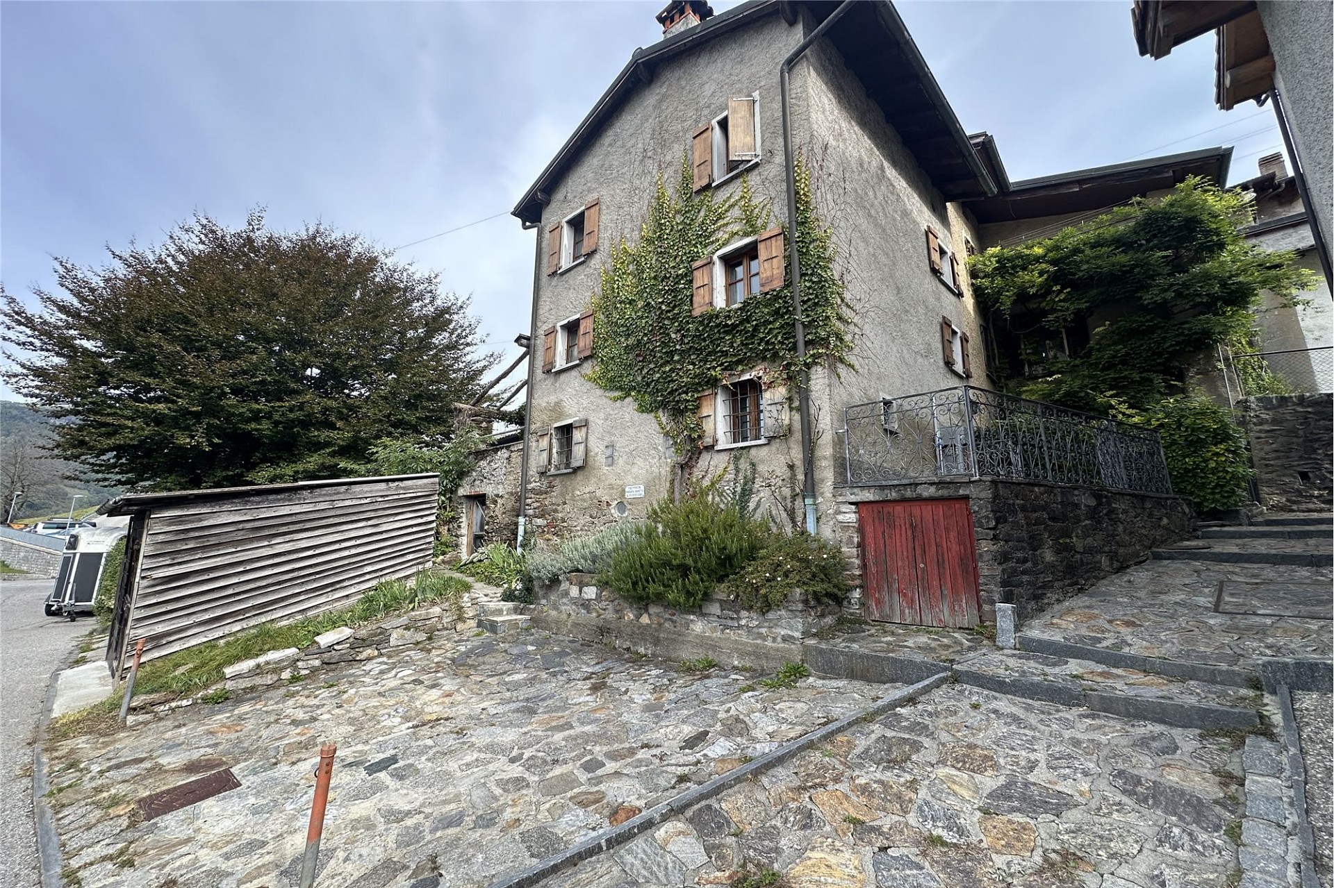 Historisches Steinhaus mit verwitterter Fassade und begrüntem Eingangshof