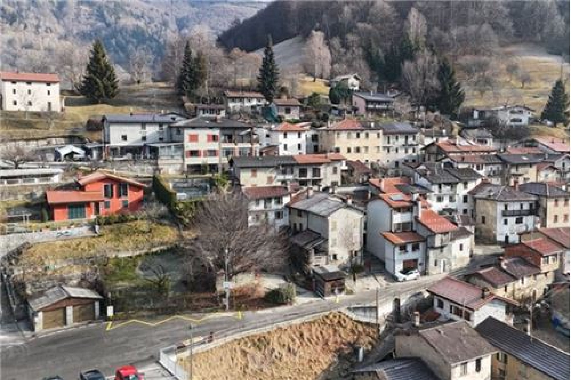 Luftaufnahme eines kleinen Dorfes in hügeliger Landschaft