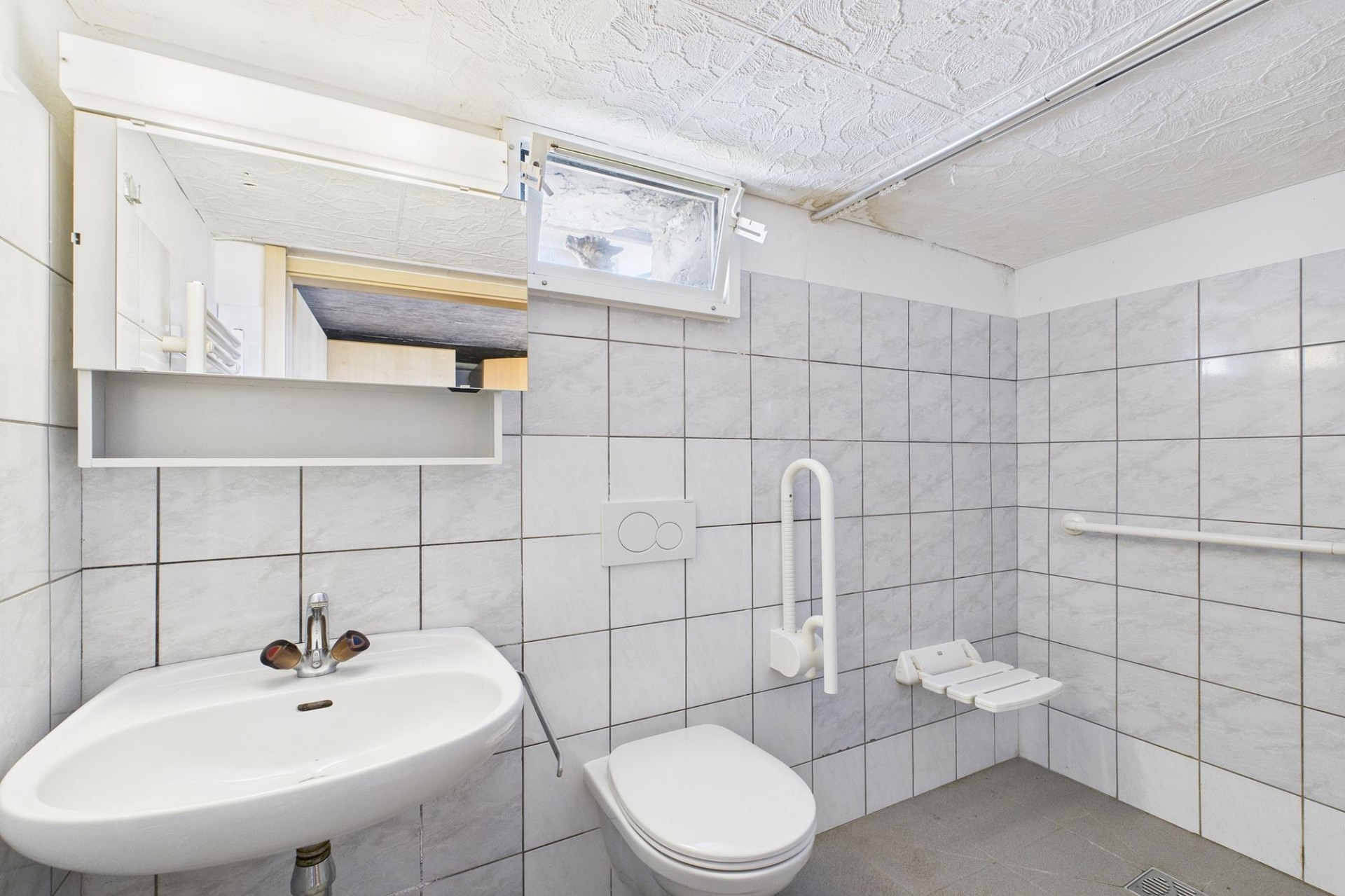 Kleines, schlichtes Badezimmer mit WC und Waschbecken