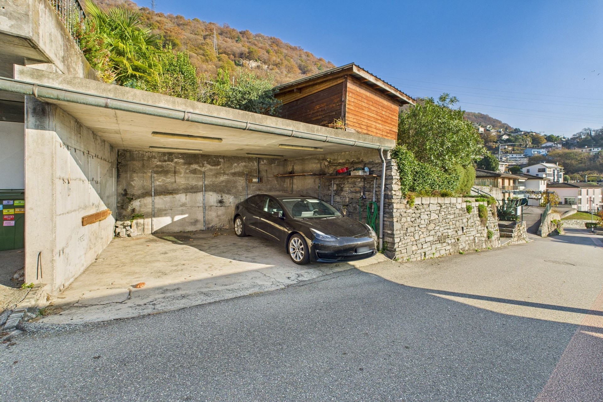 Außenansicht einer Carport- und Zufahrtsituation am Hang