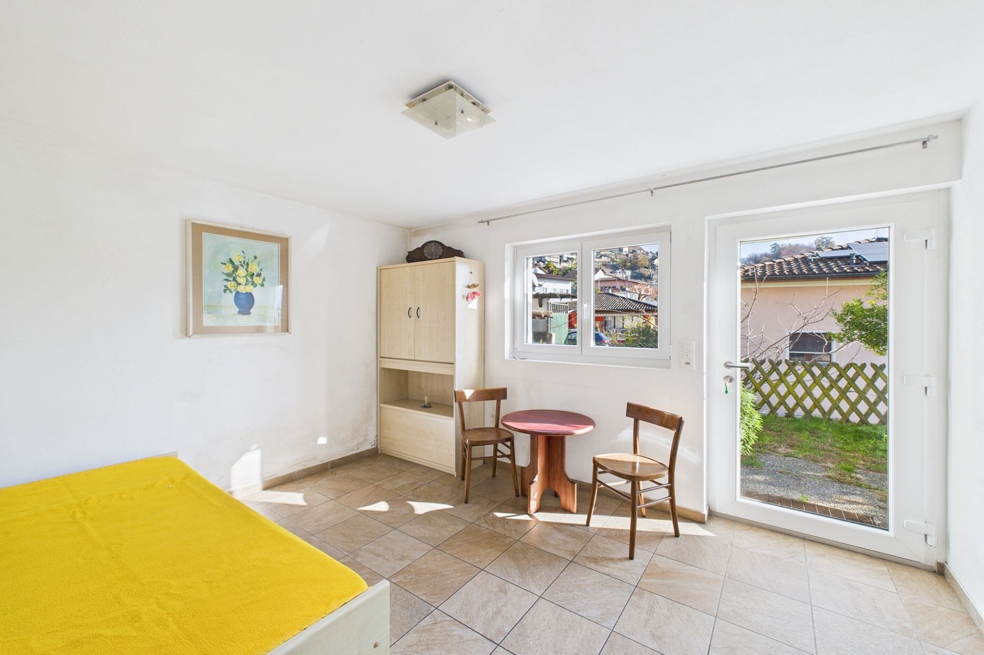 Helles, schlichtes Zimmer mit Bett, Tisch und Gartenblick