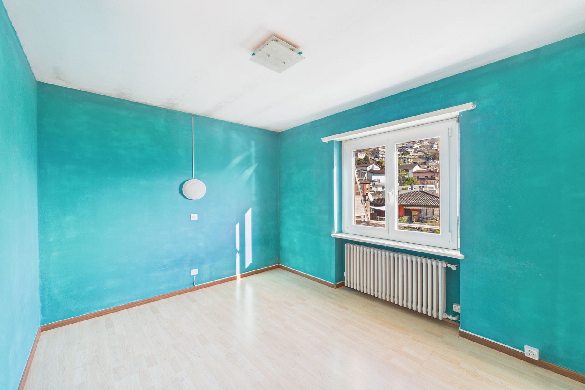Leeres Zimmer mit türkisfarbenen Wänden und Fenster