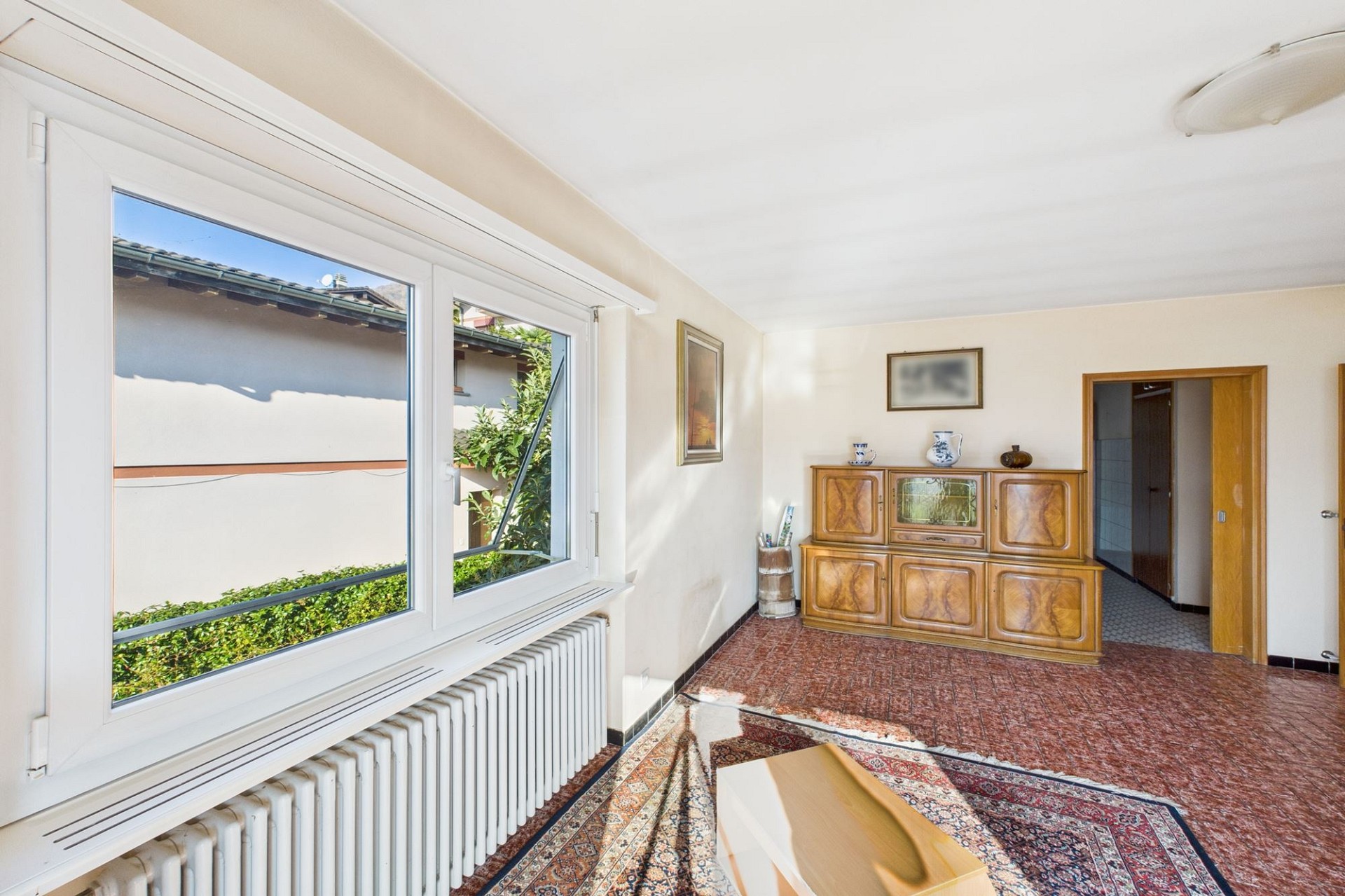 Wohnzimmer mit großem Fenster und Kommode