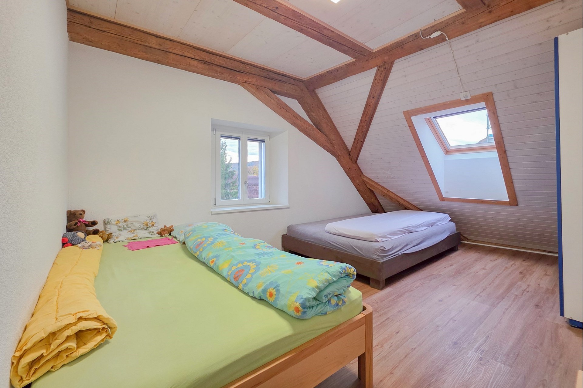 Dachgeschoss-Schlafzimmer mit sichtbaren Holzbalken