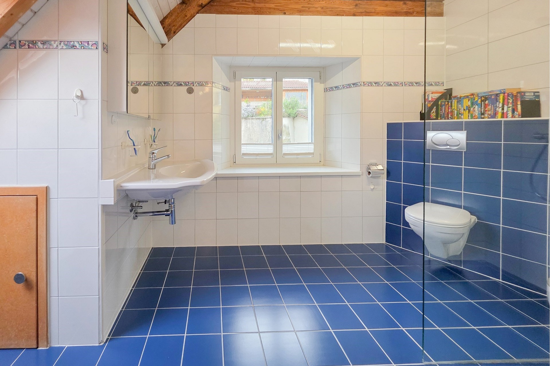 Badezimmer mit blauen Bodenfliesen und Holzdecke