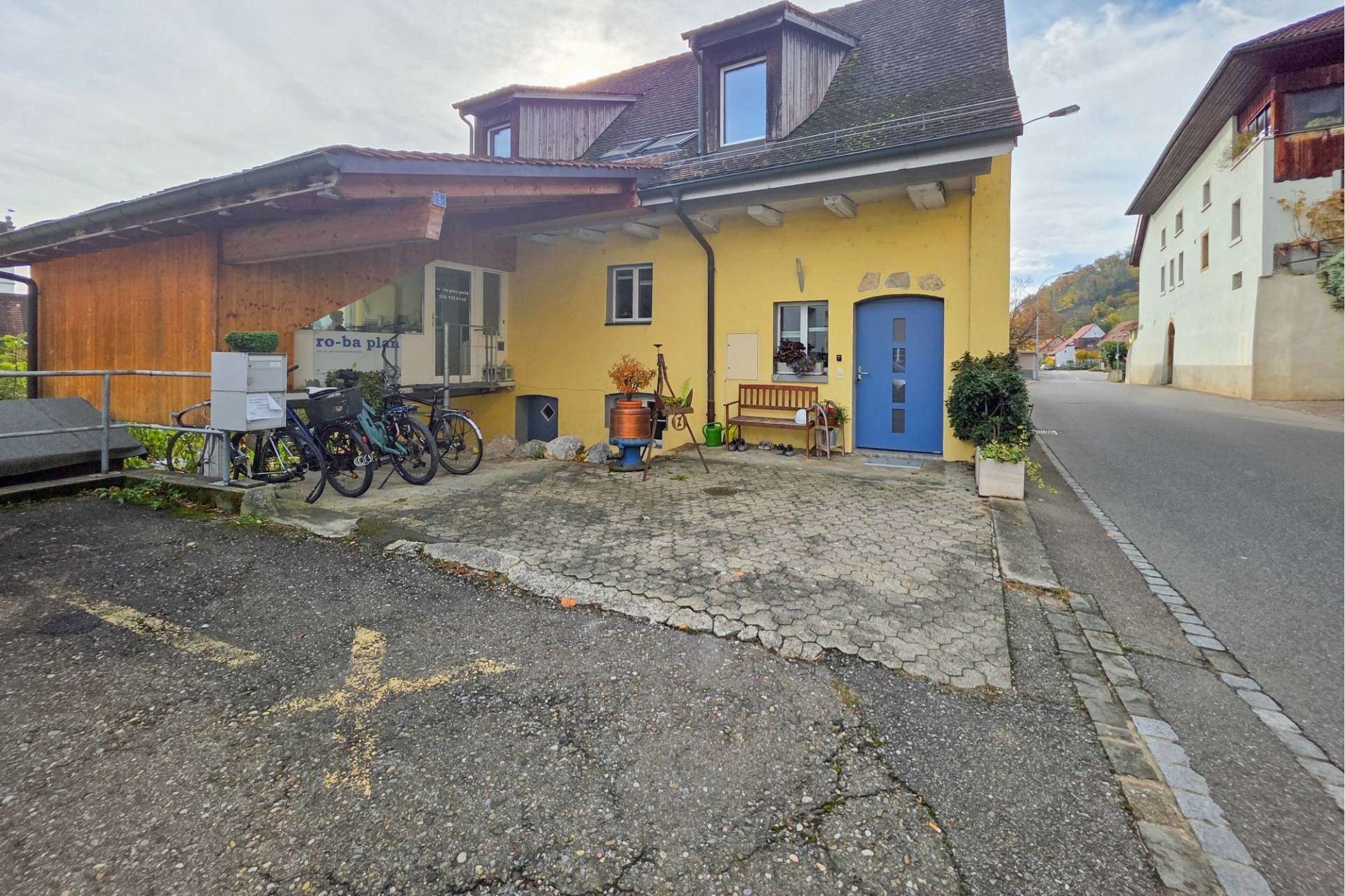 Straßenansicht eines Hauses mit Vorgarten und Nebentrakt