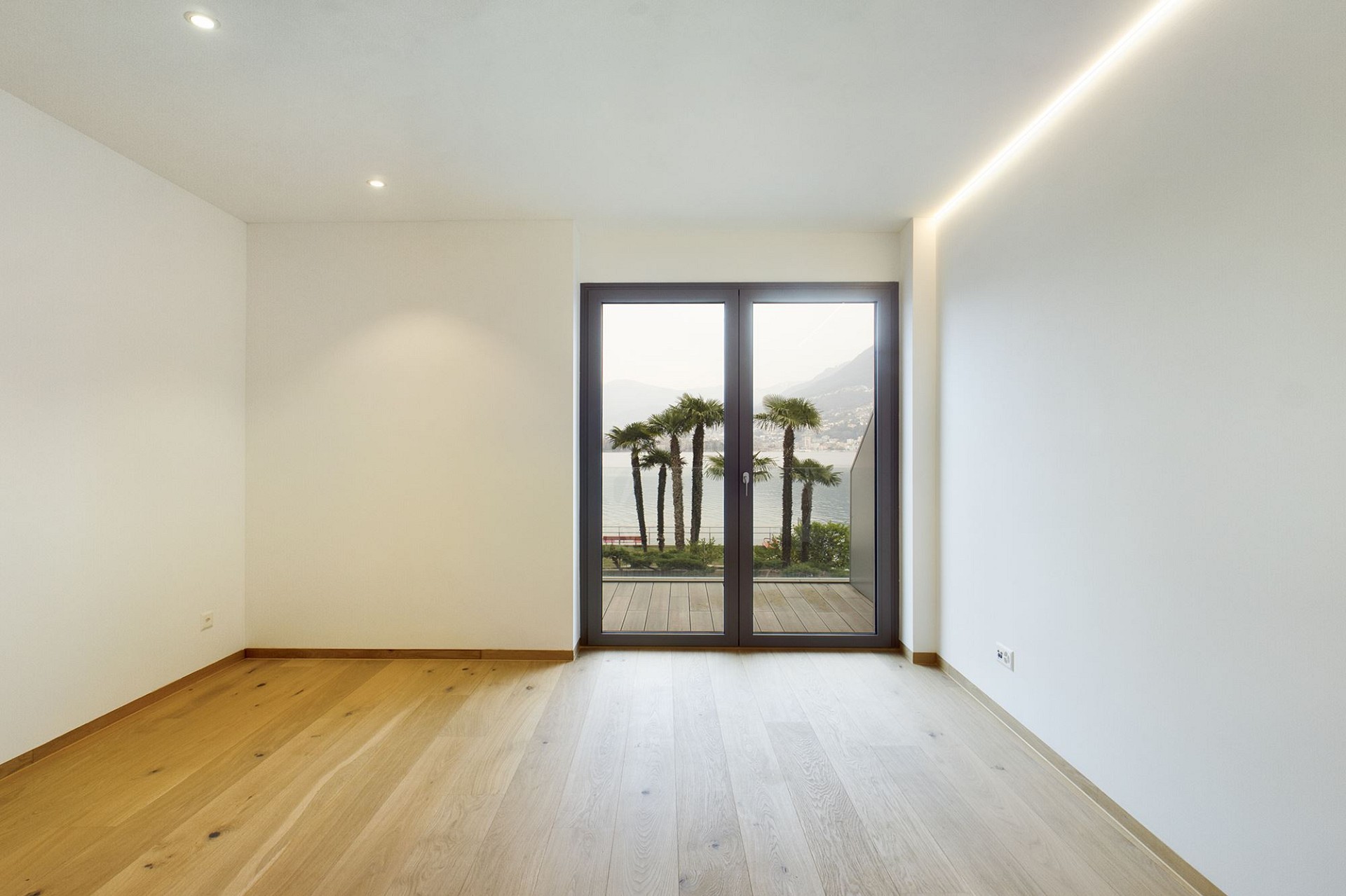 Heller leerer Wohnraum mit Blick auf Wasser und Palmen