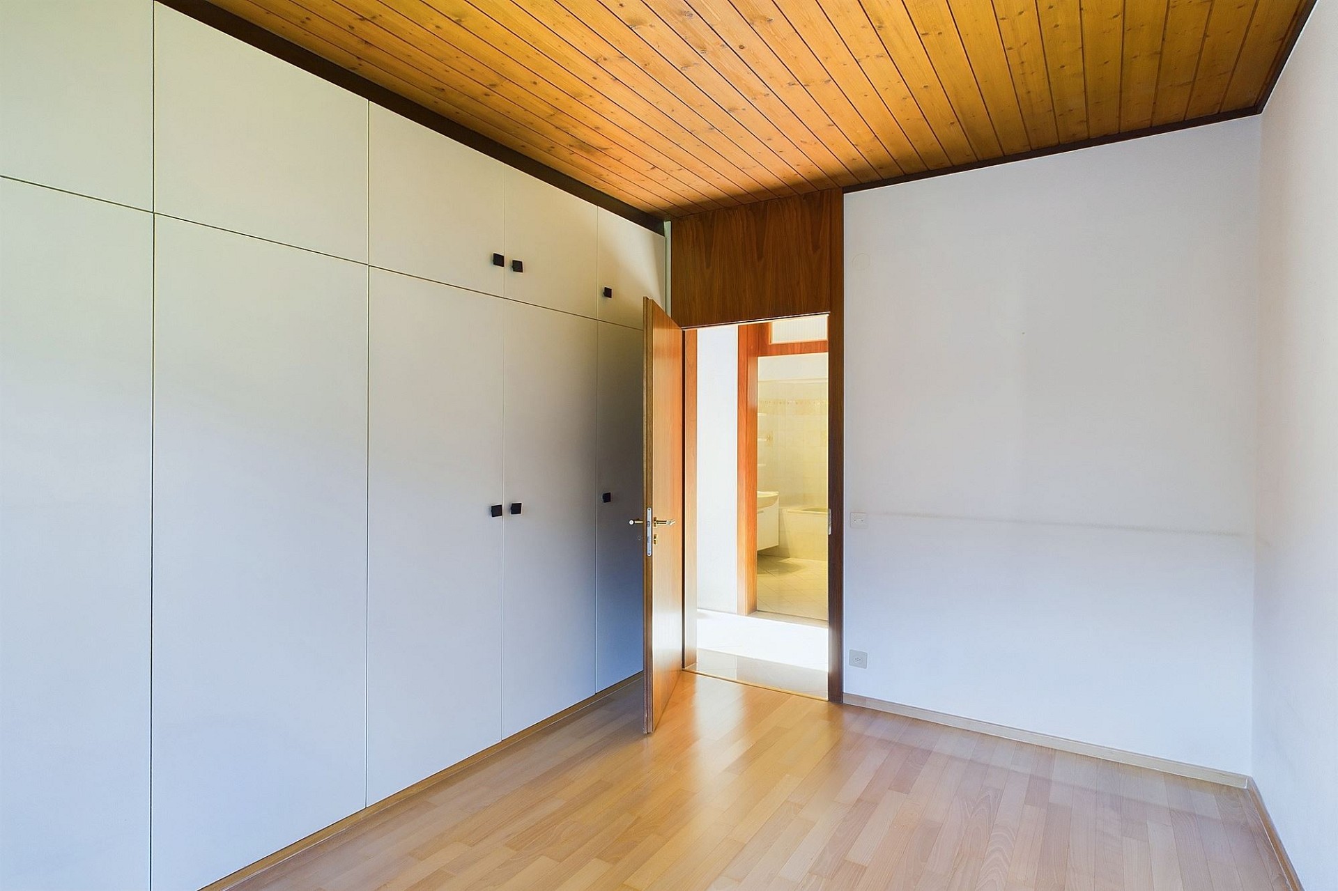 Helles Schlafzimmer mit Einbauschränken und Holzdecke