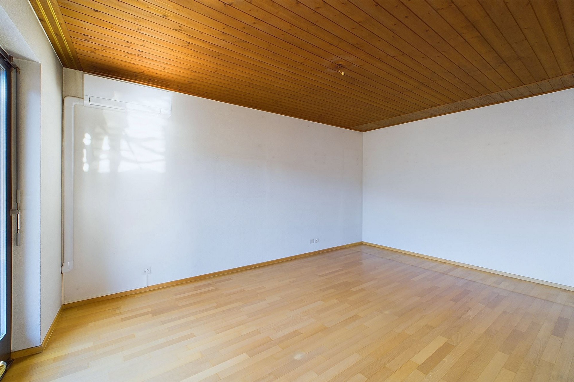Leerer Raum mit Holzdecke und Parkettboden