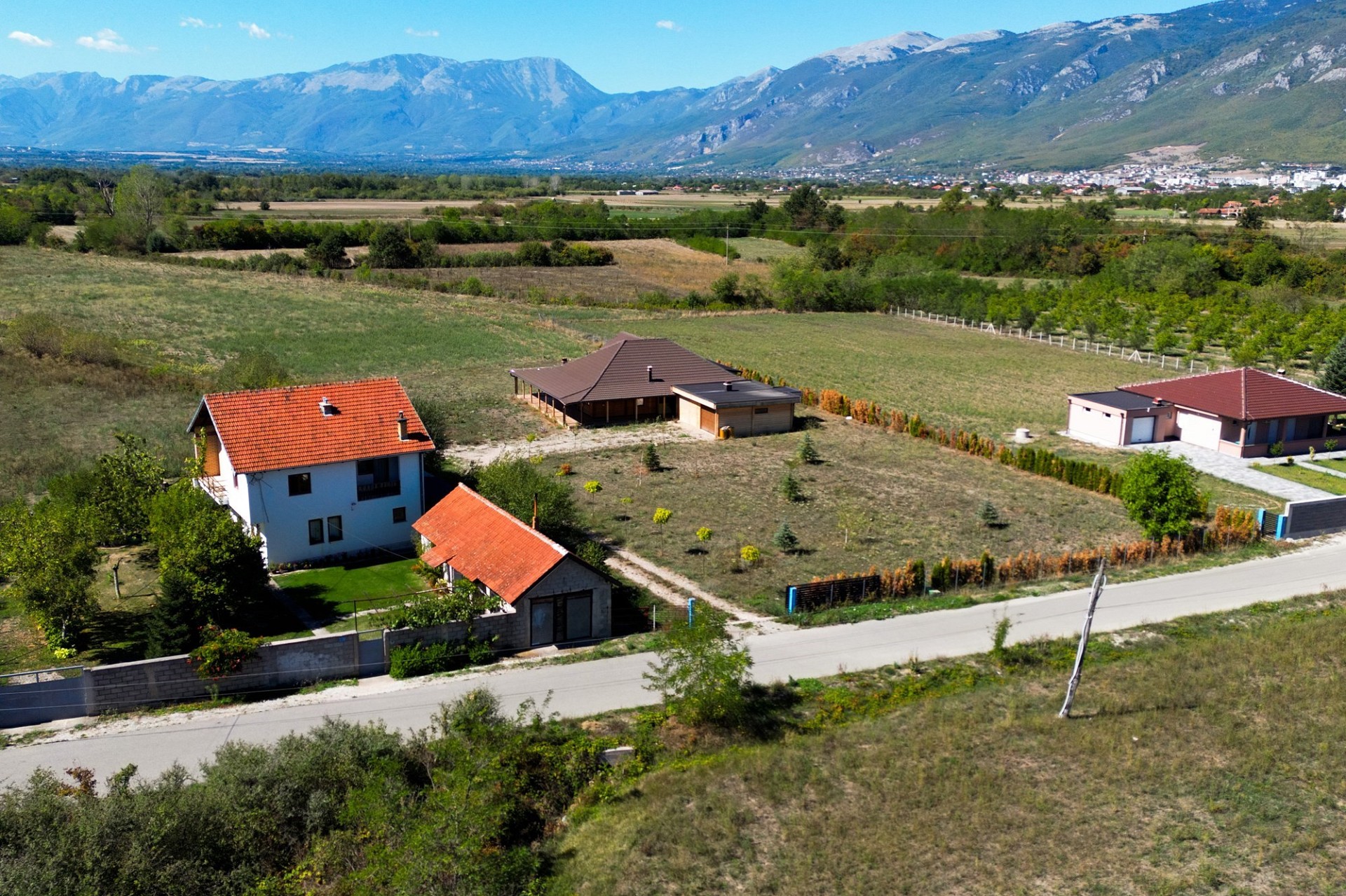 Luftaufnahme eines ländlichen Grundstücks mit Häusern und Bergpanorama