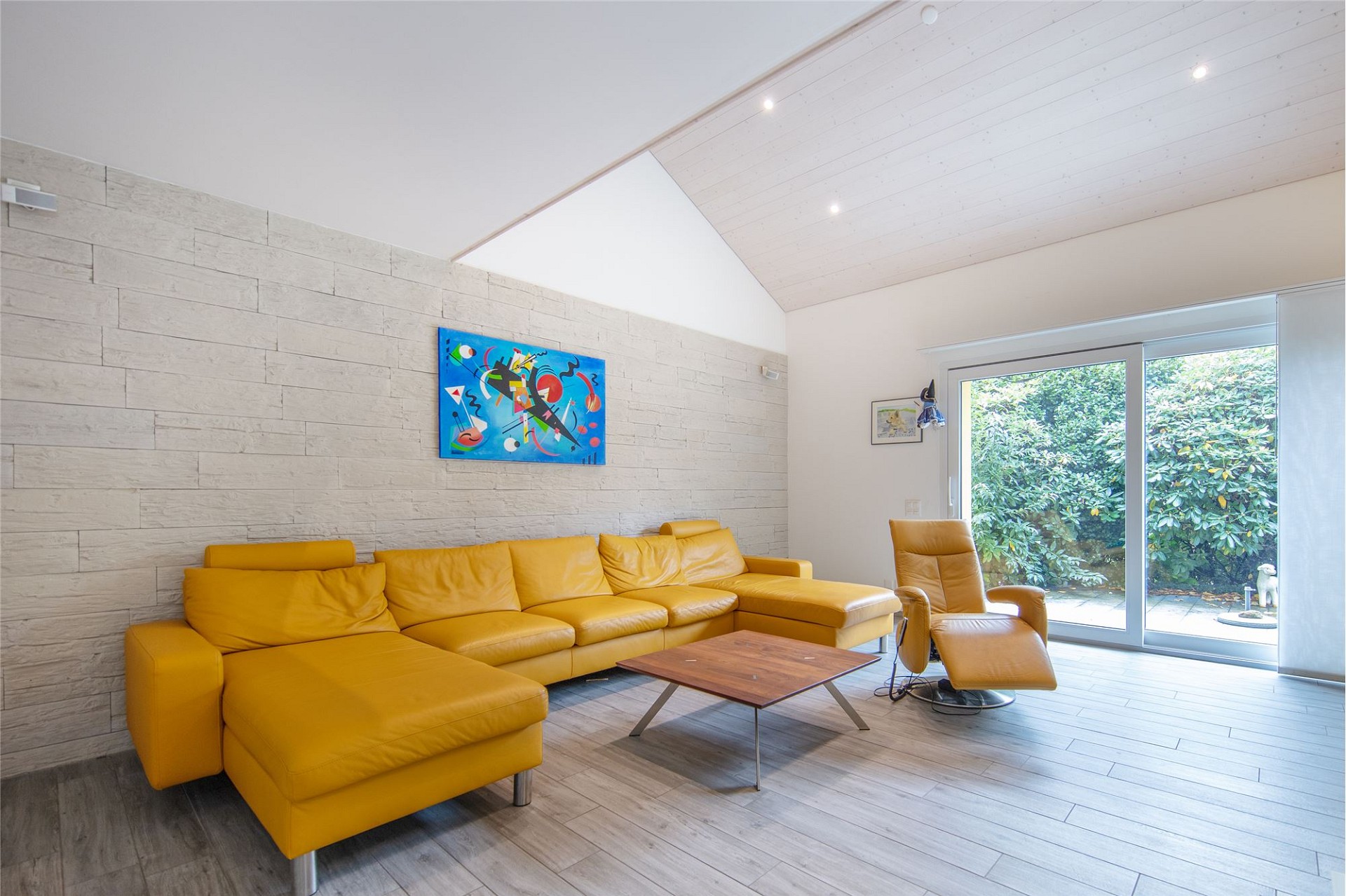 Heller Wohnraum mit gelbem Sofa und Gartenblick