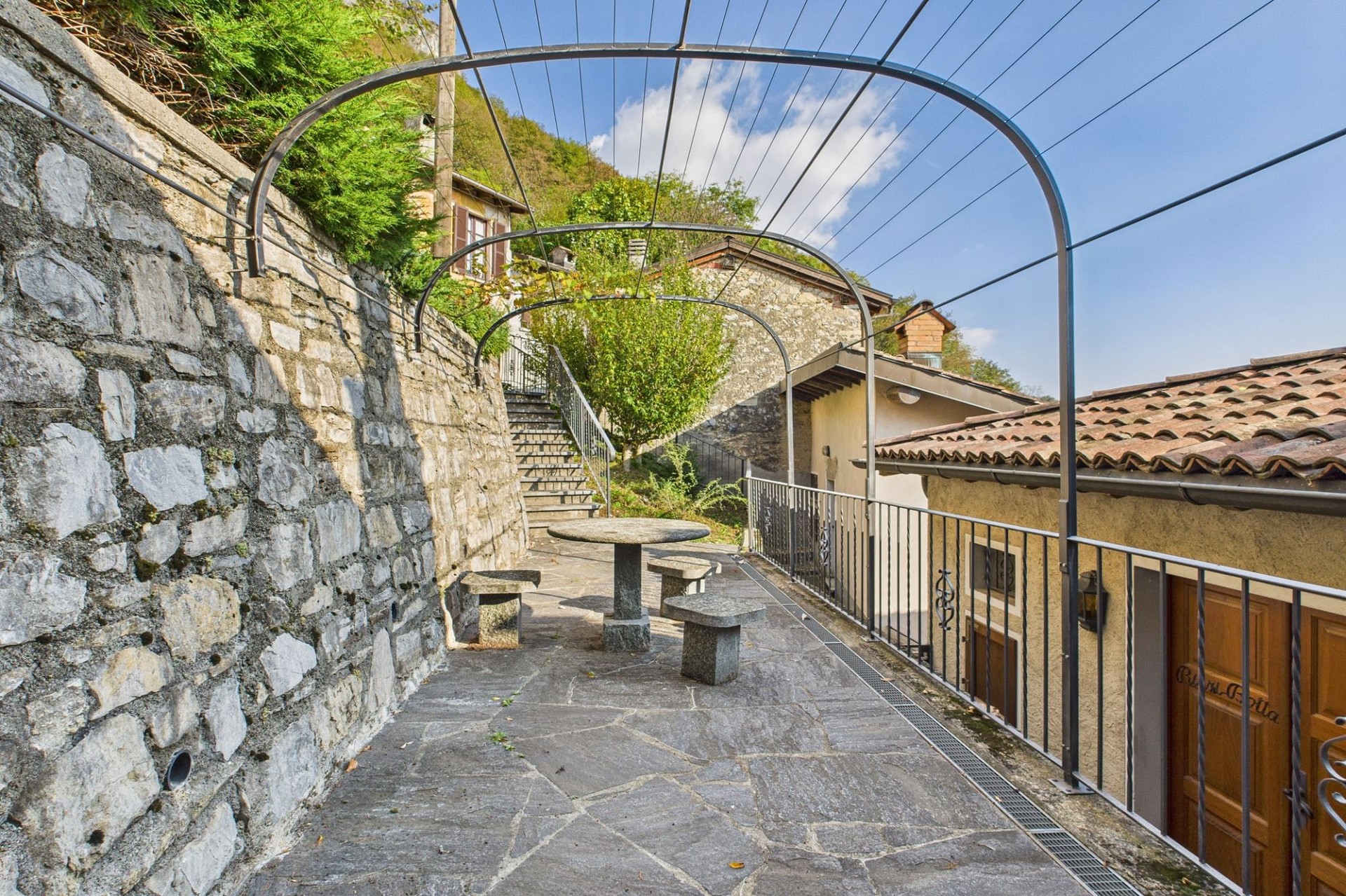 Steinverkleidete Terrasse mit Pergola-Rahmen