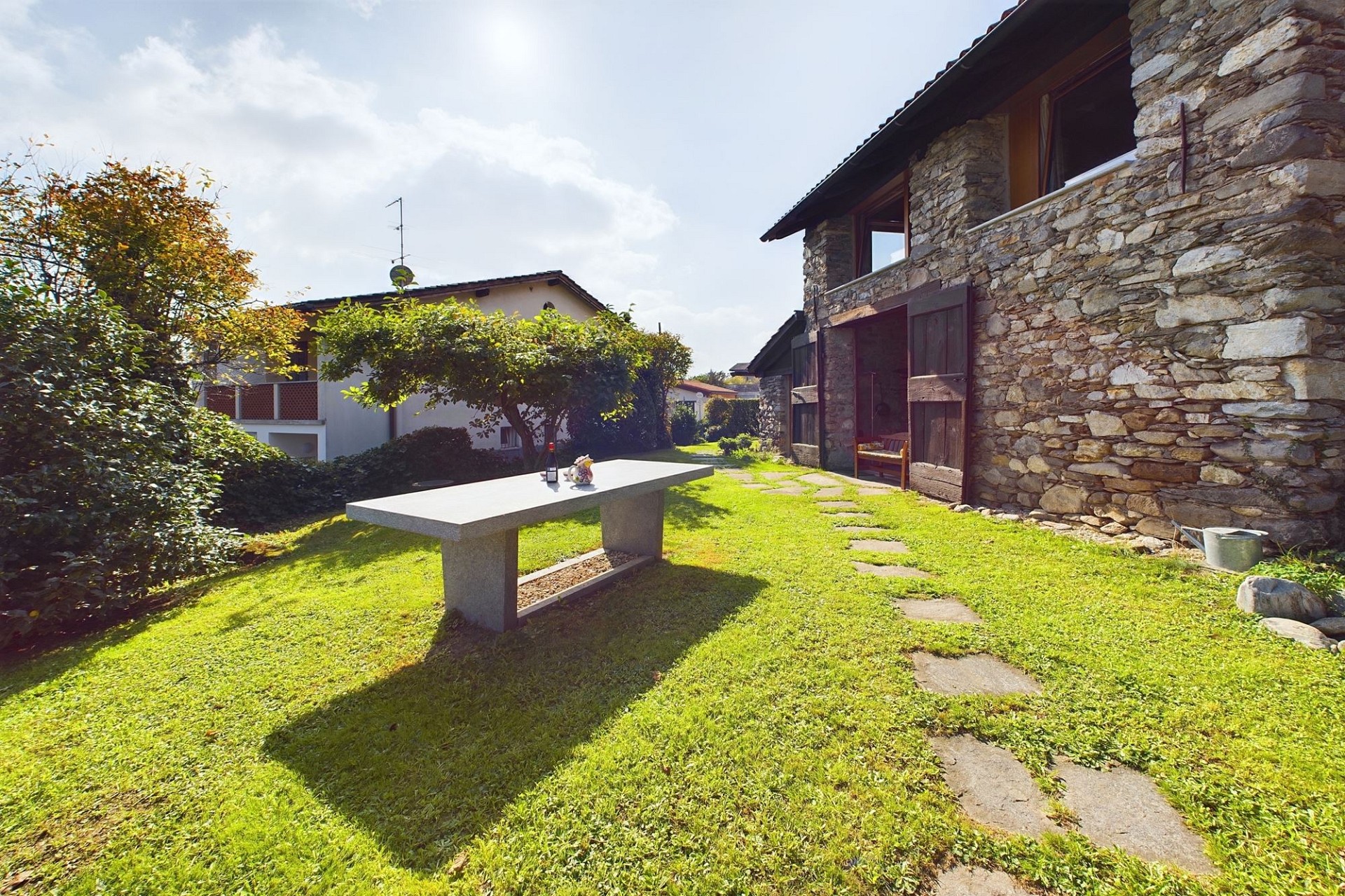 Rustikaler Garten mit Steintisch vor einem Haus