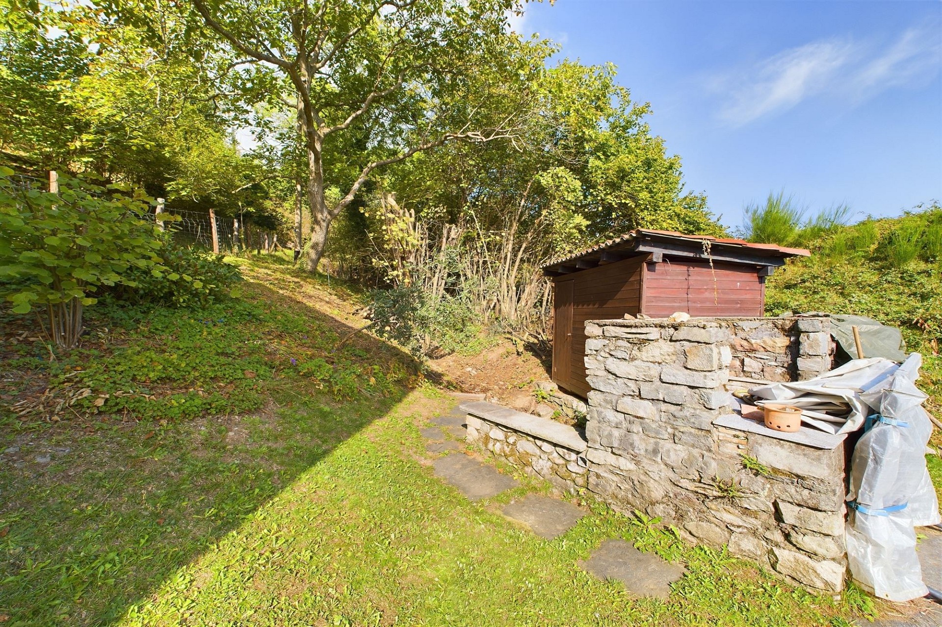 Garten mit steinerner Einfassung und Holzschuppen