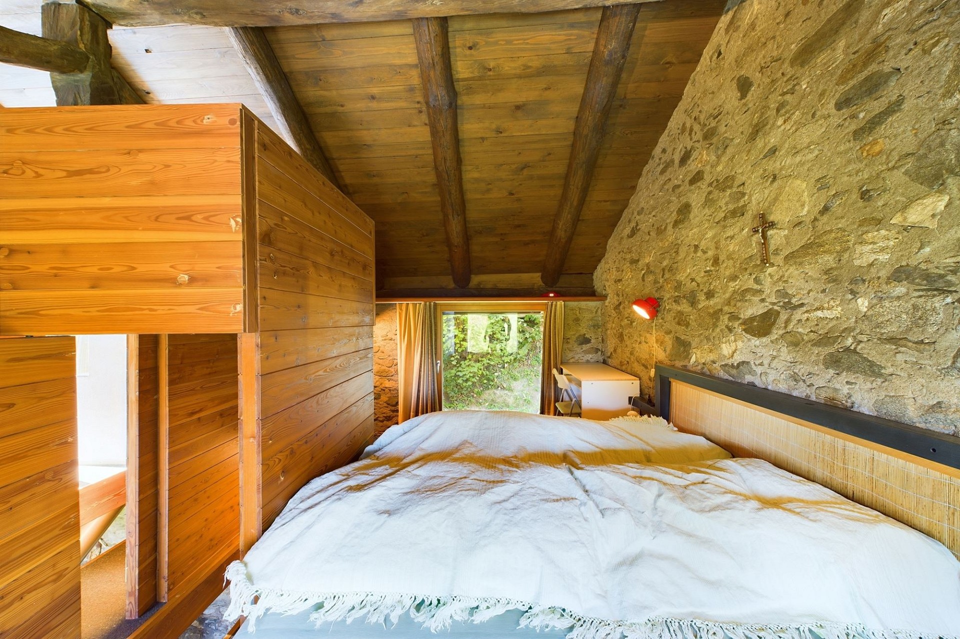 Rustikales Schlafzimmer mit Natursteinwand und Holzbalkendecke