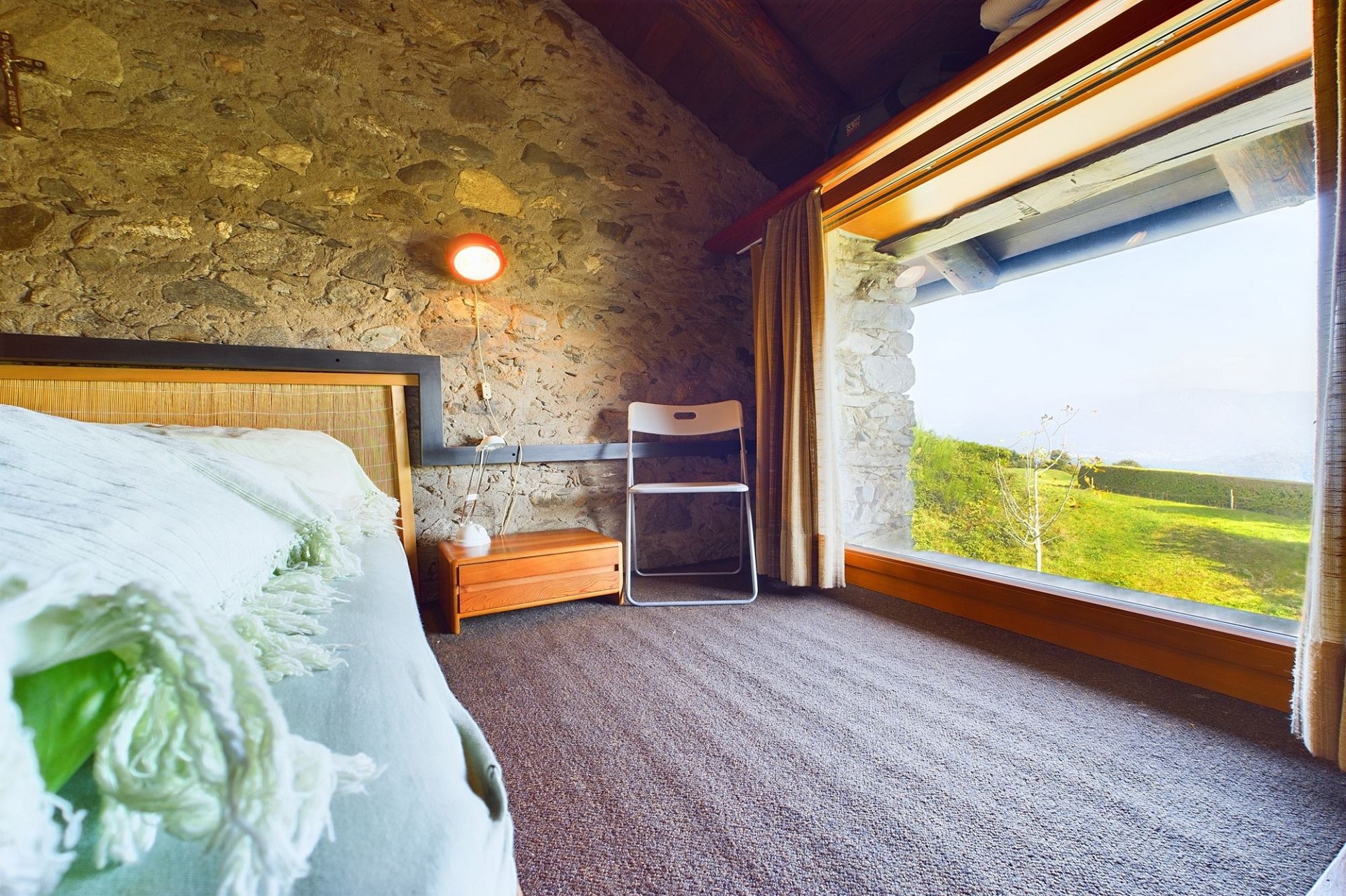 Gemütliches Schlafzimmer mit Natursteinwand und Panoramafenster