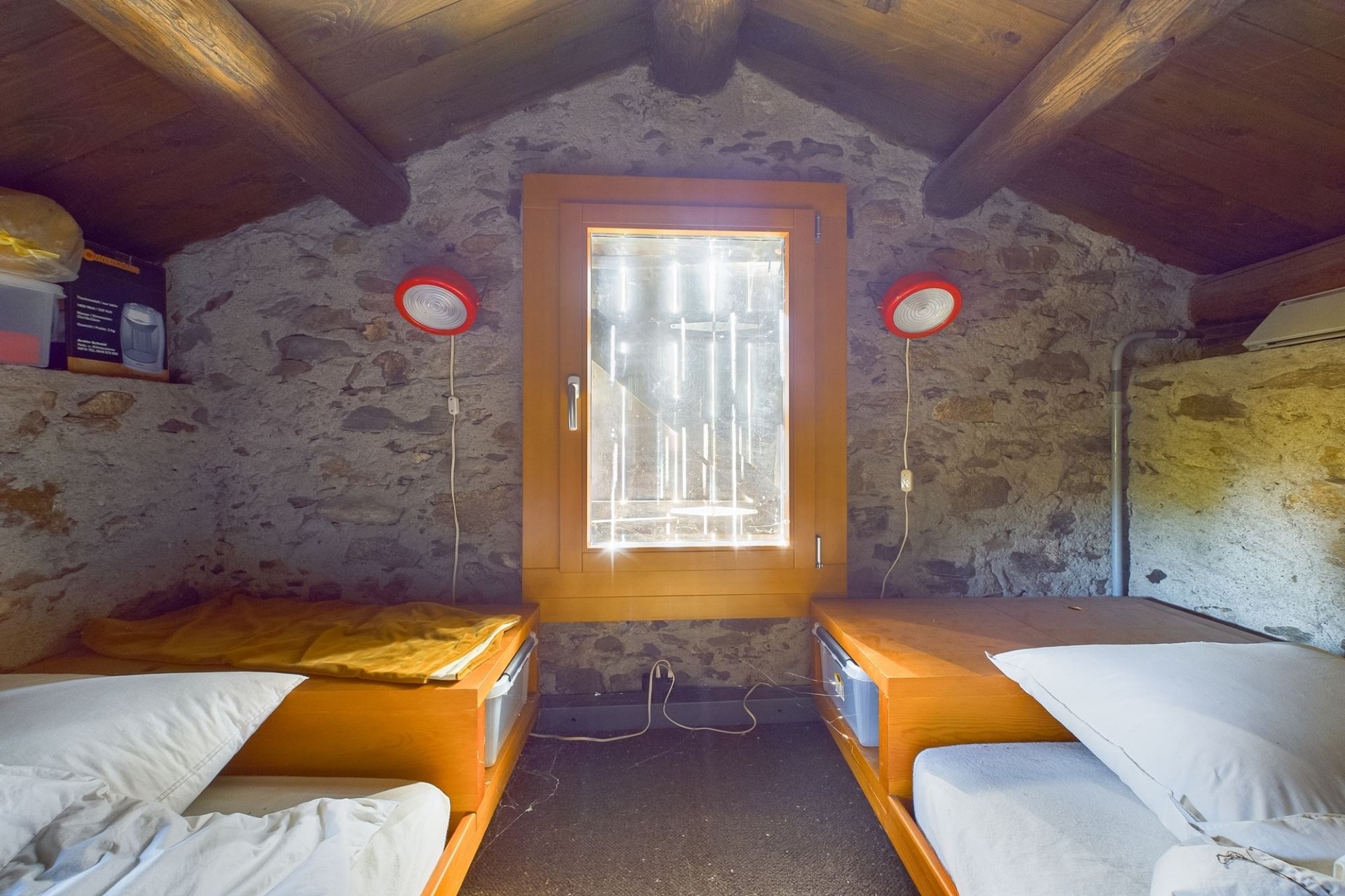 Rustikales Schlafzimmer mit Steinwänden und Holzbalken