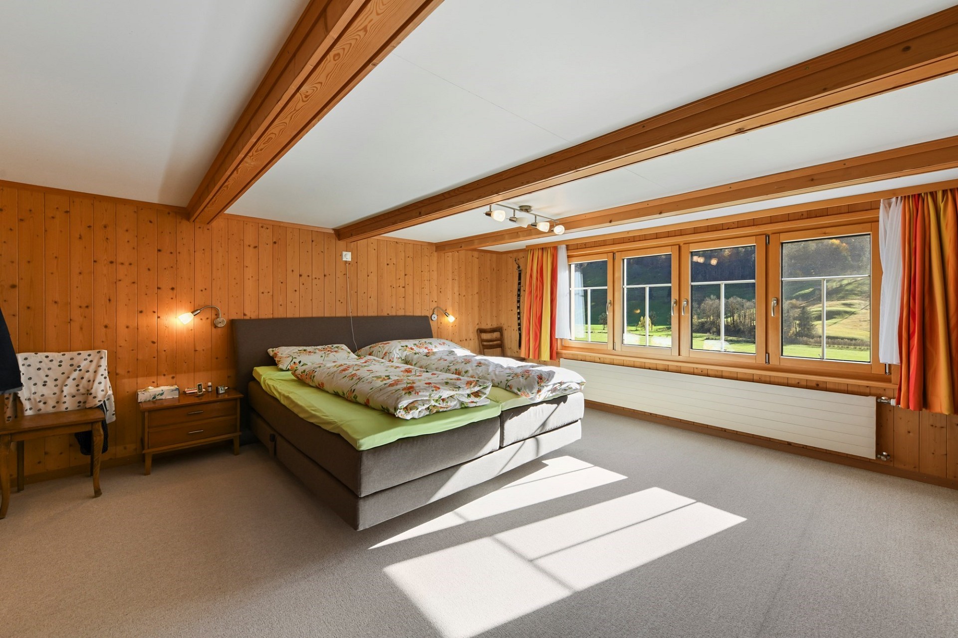 Helles Schlafzimmer mit Holzvertäfelung und Blick ins Grüne