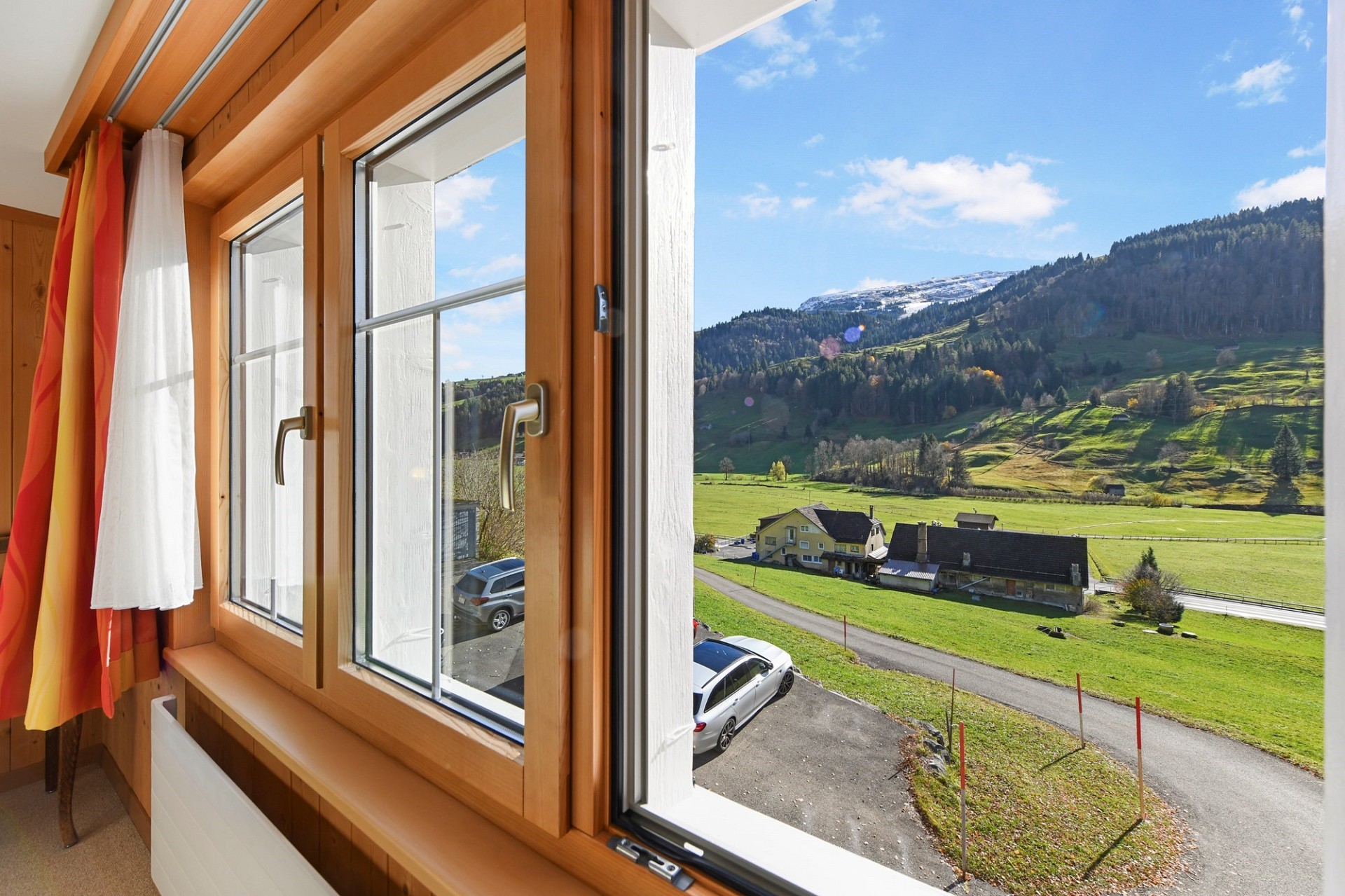 Blick aus einem holzverkleideten Innenraum ins Alpenpanorama