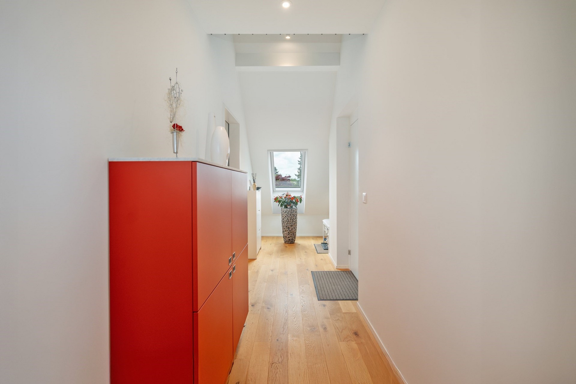 Heller, moderner Flur mit rotem Sideboard