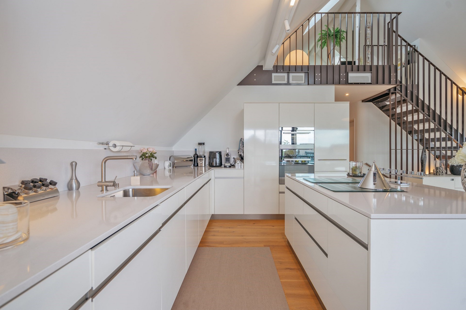 Moderne, helle Wohnküche mit Galerie und Treppe