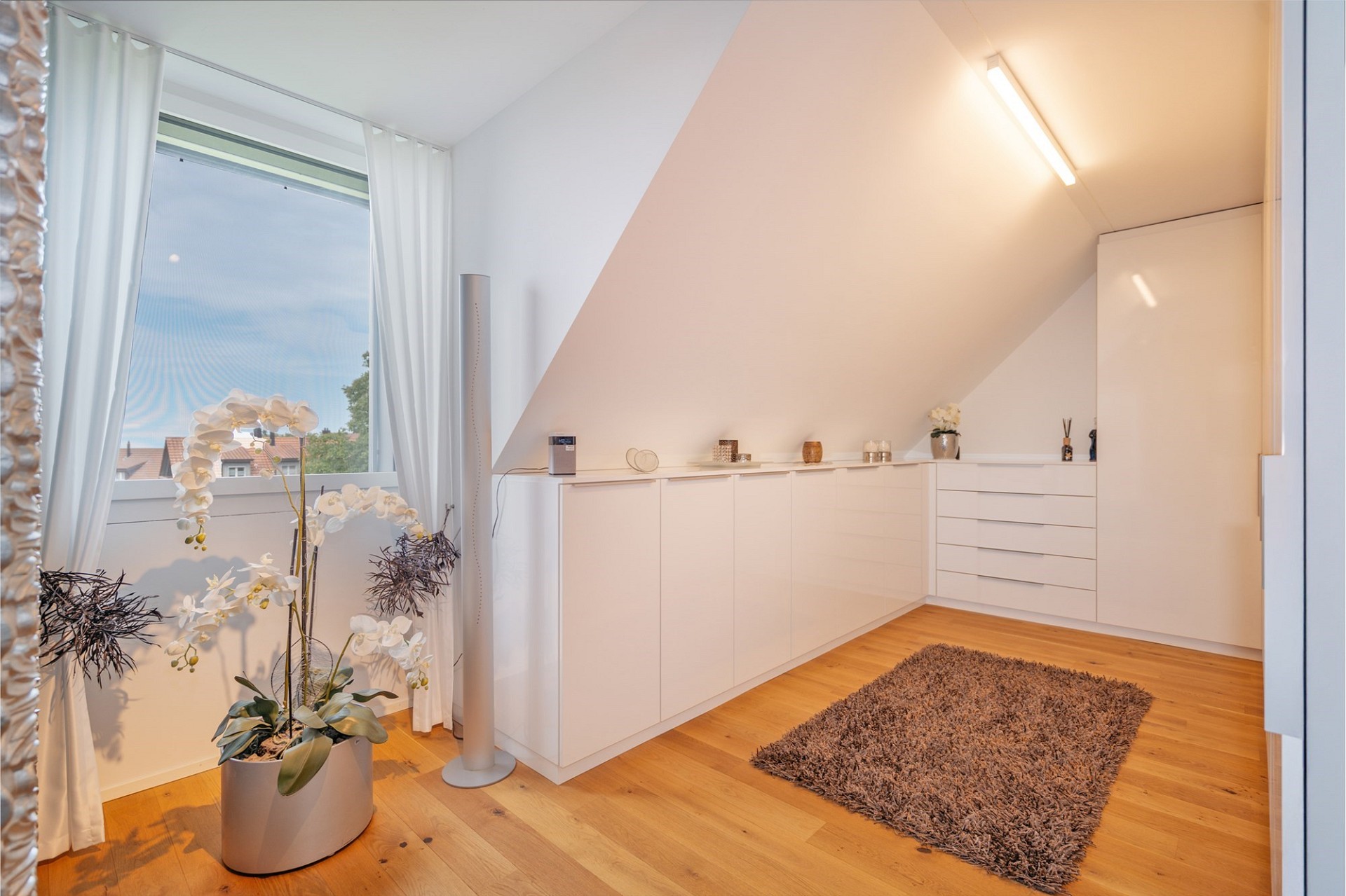Helles Dachgeschosszimmer mit weißem Einbau und Blick ins Freie