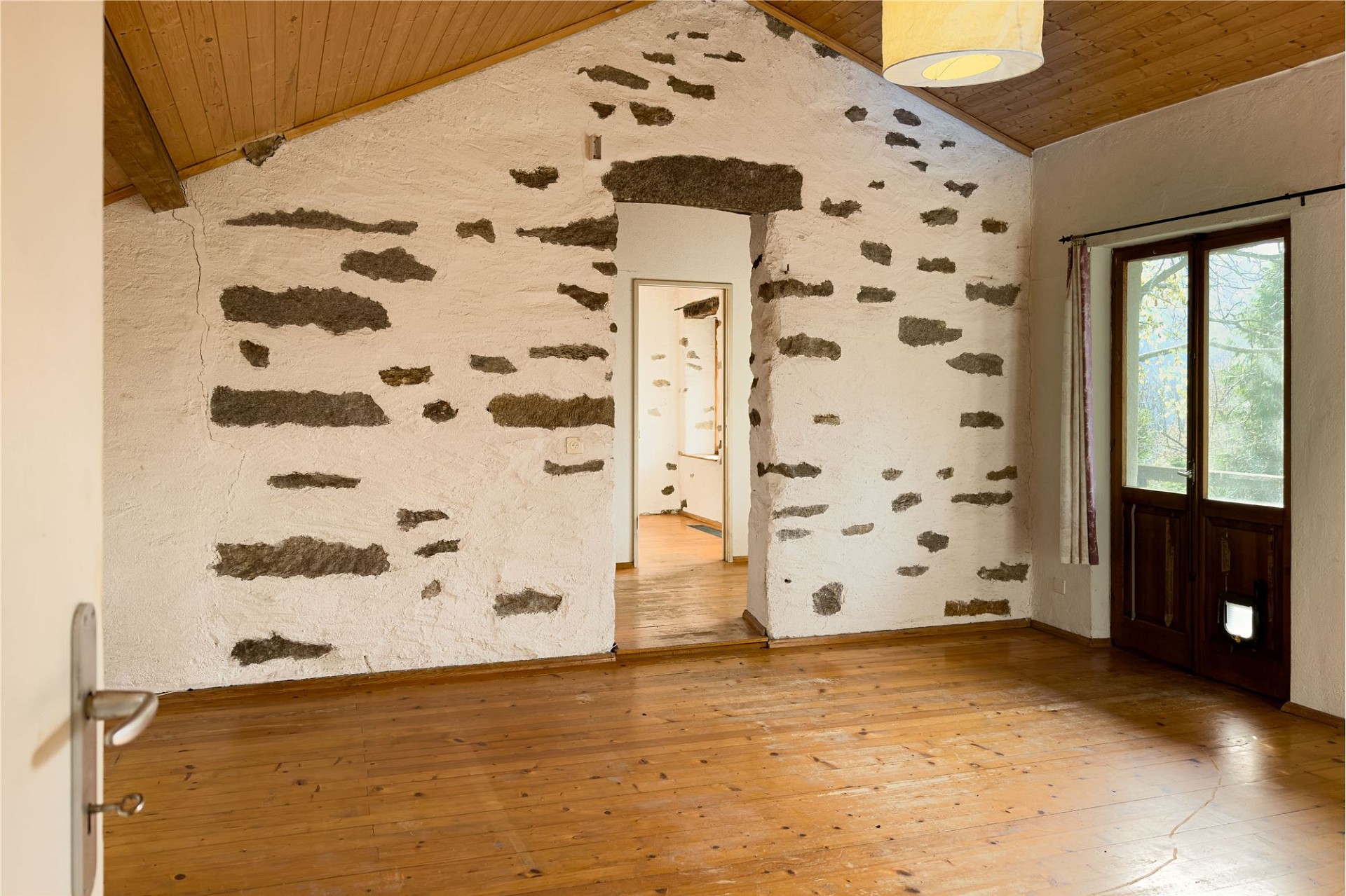Rustikaler Raum mit Holzdecke und Natursteinwand