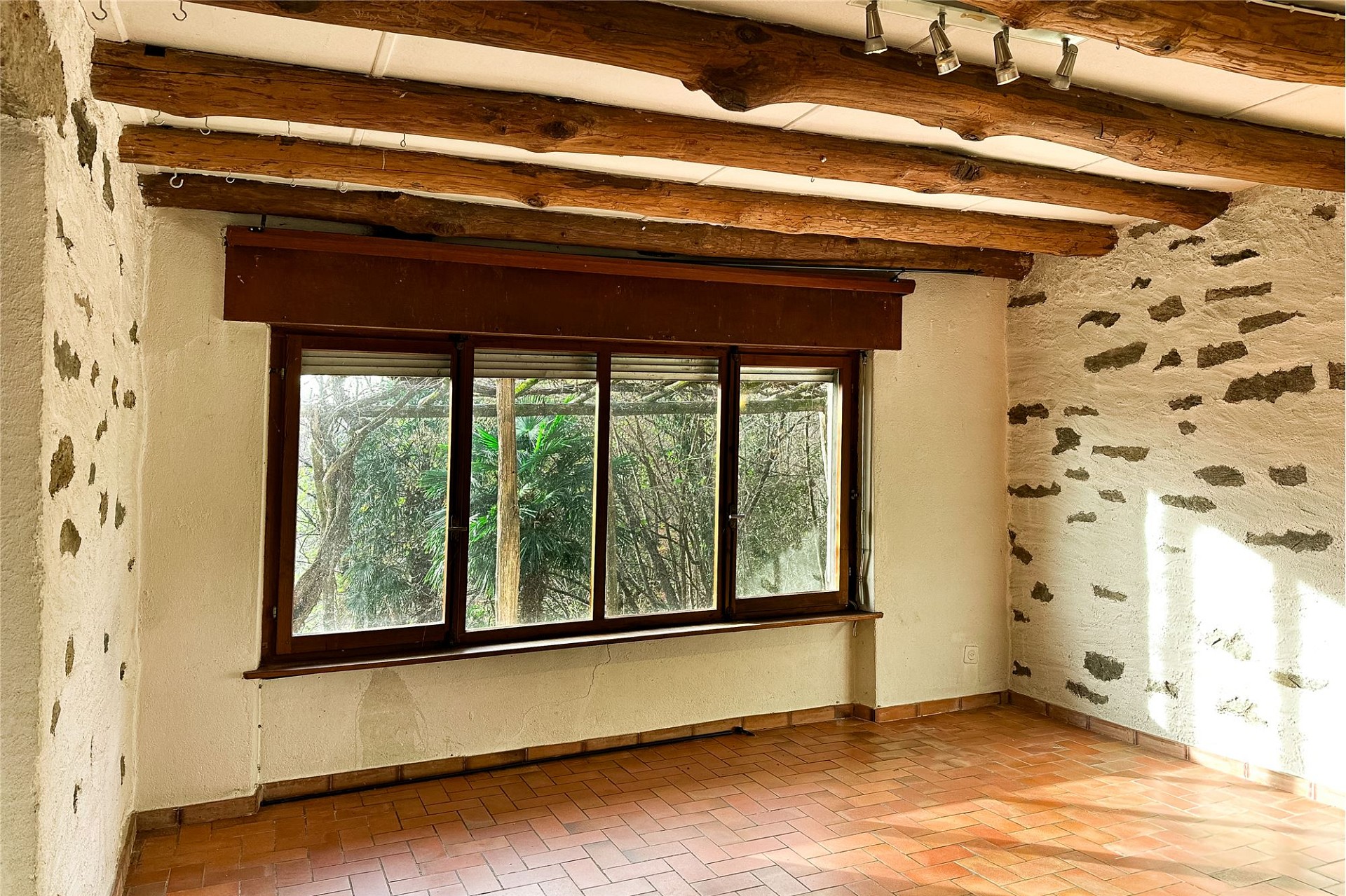 Rustikaler Raum mit Holzdeckenbalken und Natursteinwänden