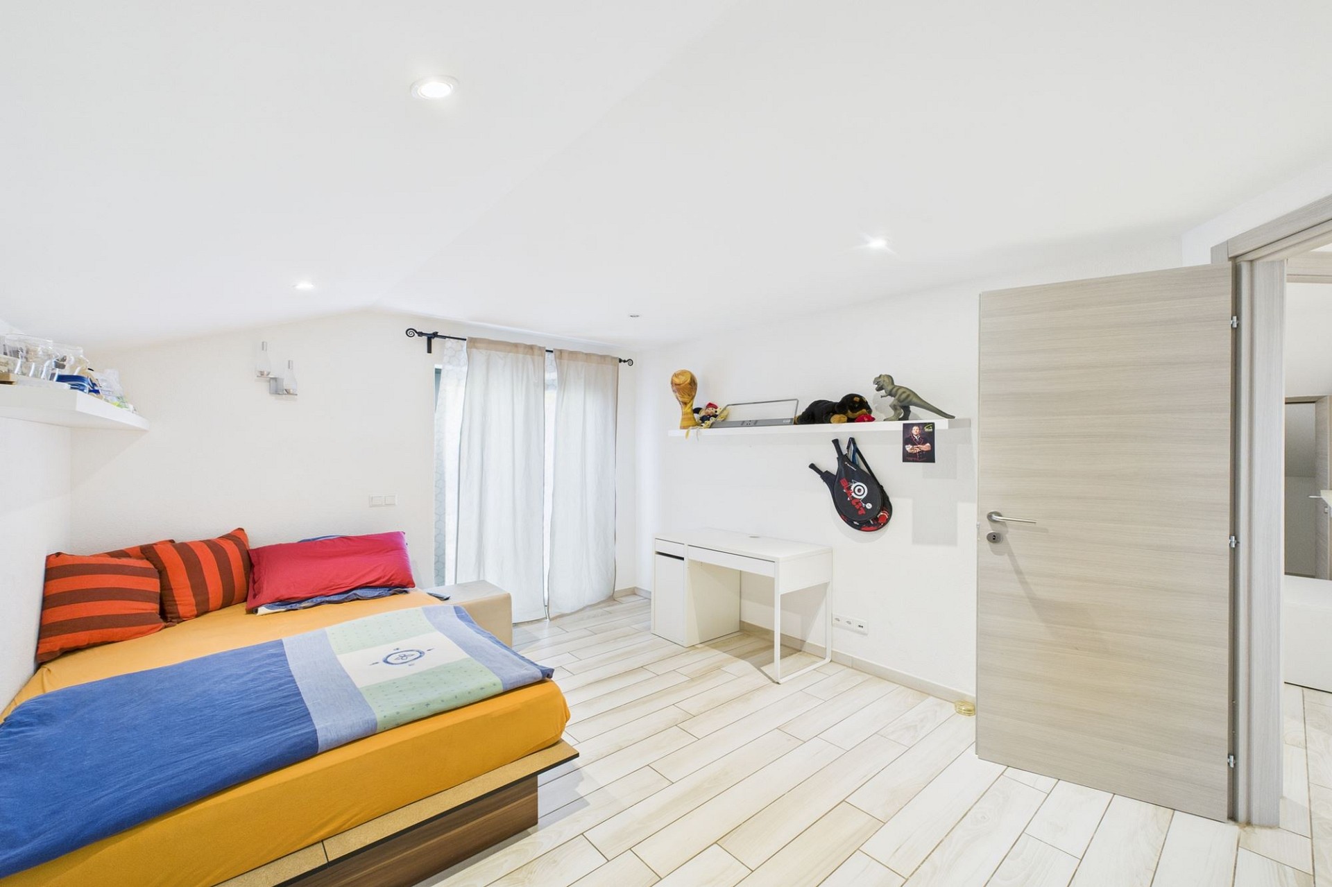 Helles Schlafzimmer mit Doppelbett und Schreibtisch