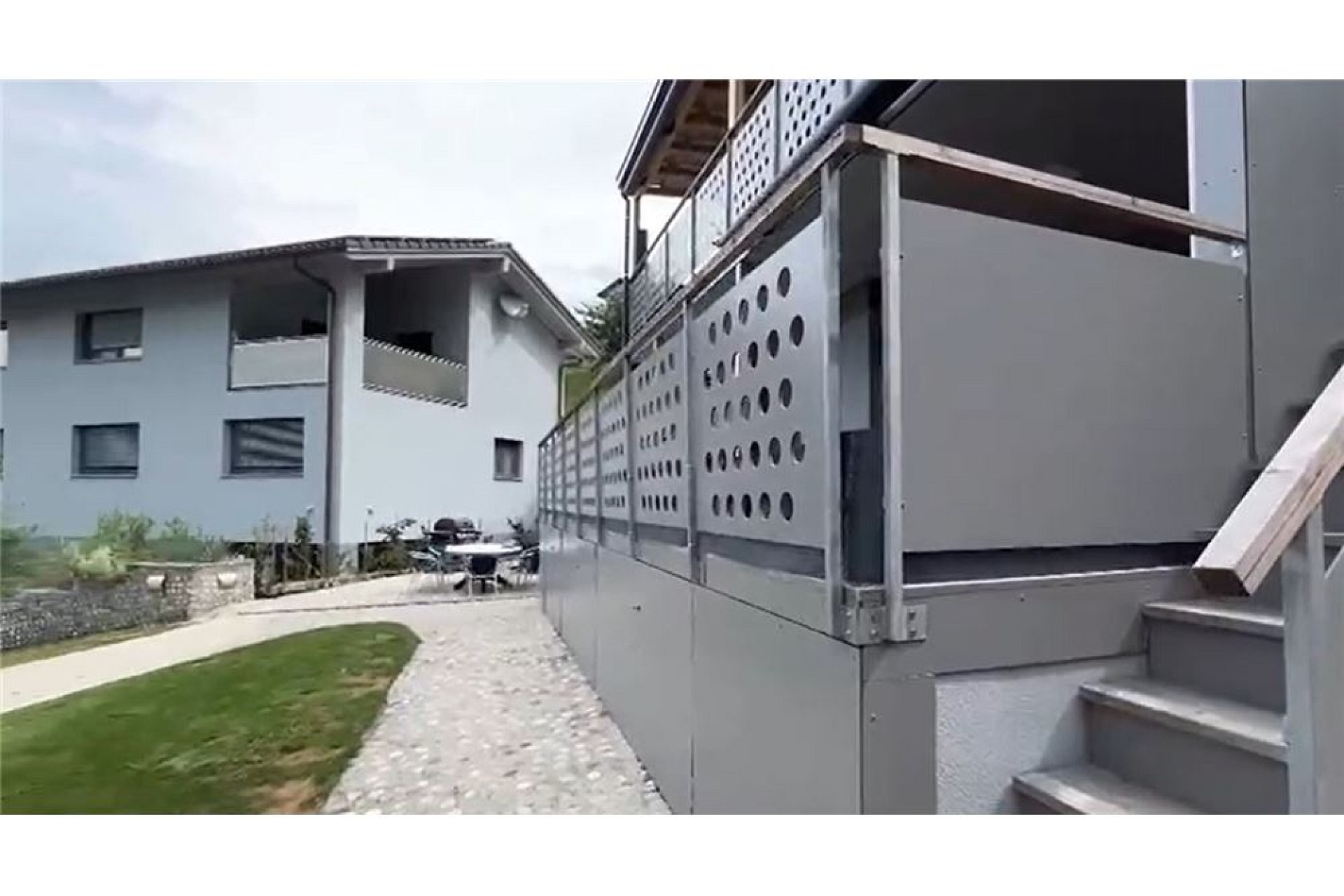 Außenansicht eines modernen Gebäudekomplexes mit Balkon und Weg