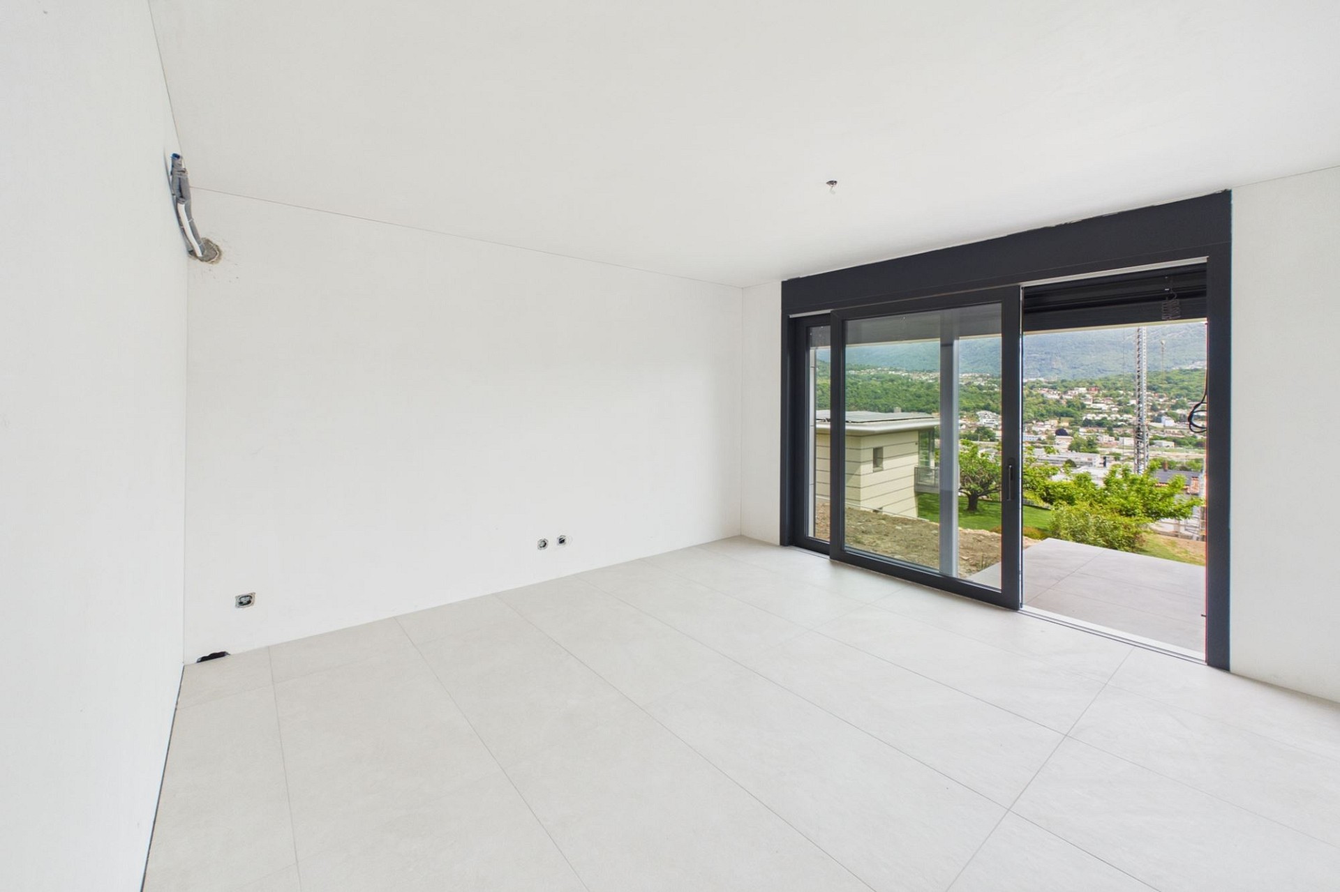 Leerer moderner Wohnraum mit großer Schiebetür und Ausblick