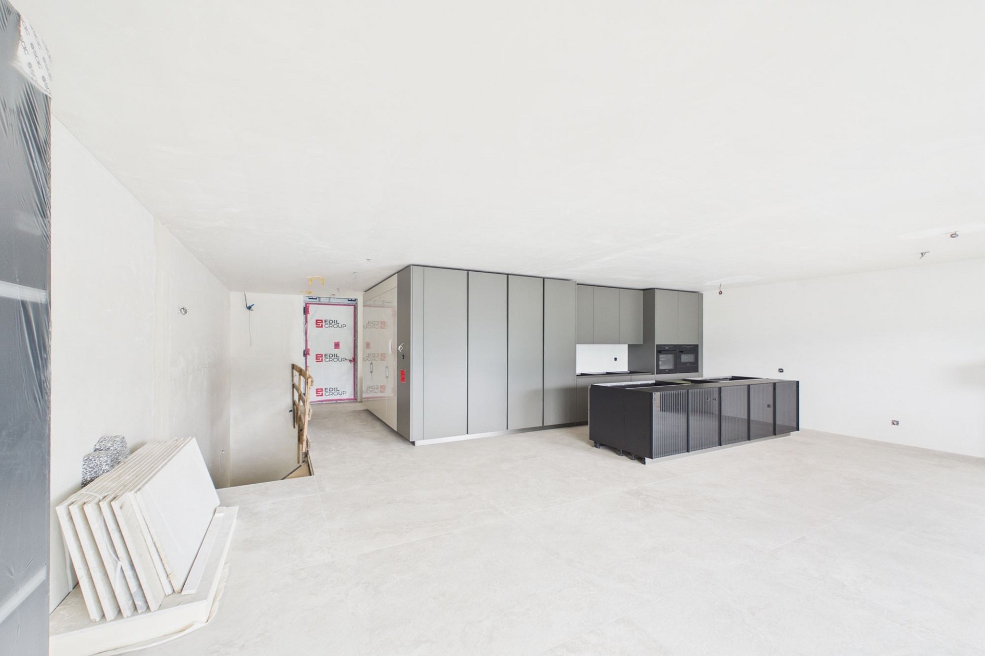 Unvollendeter Wohnraum mit offener Treppe und Küche