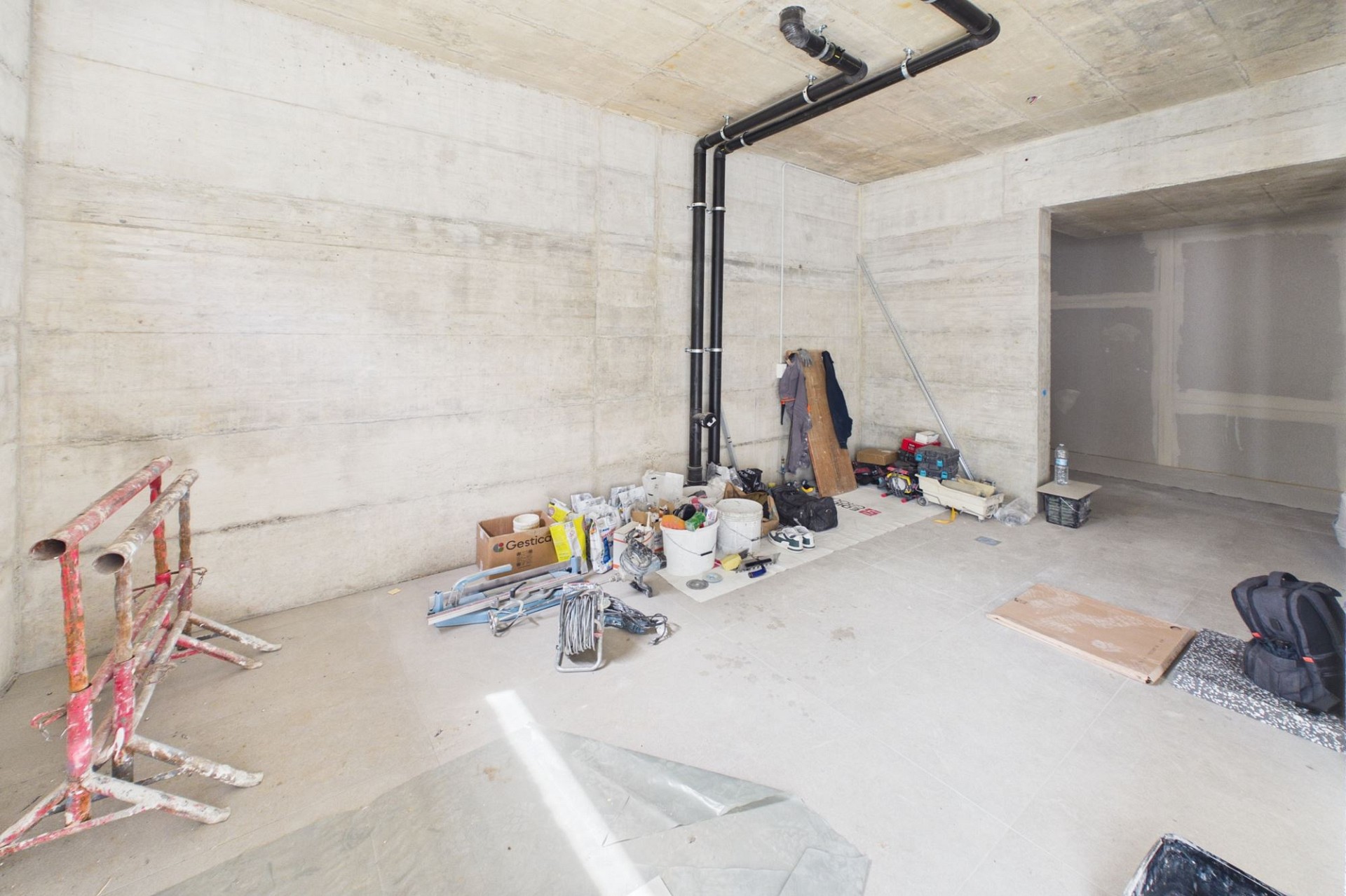Rohbauartiger Kellerraum mit Baumaterial und Leitungen